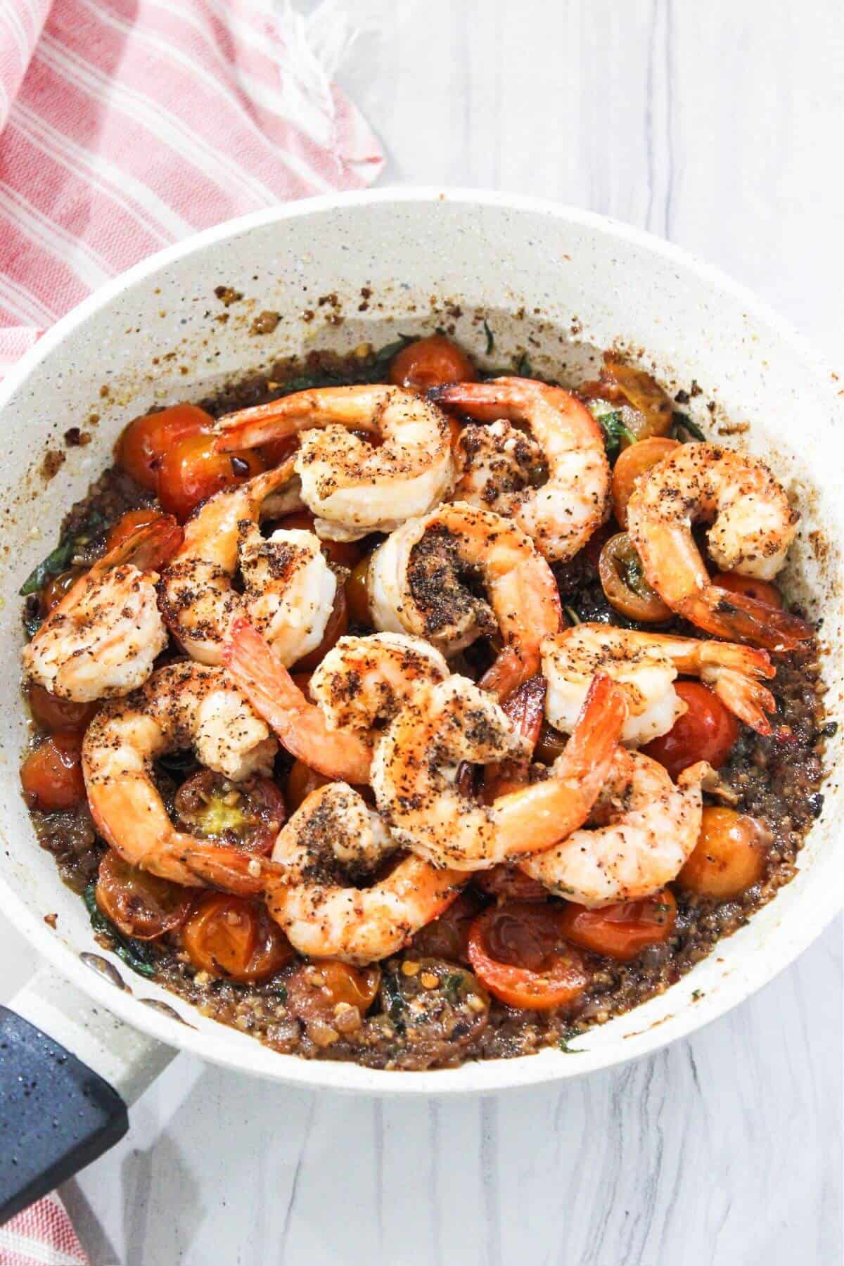 A skillet filled with shrimp and tomatoes.