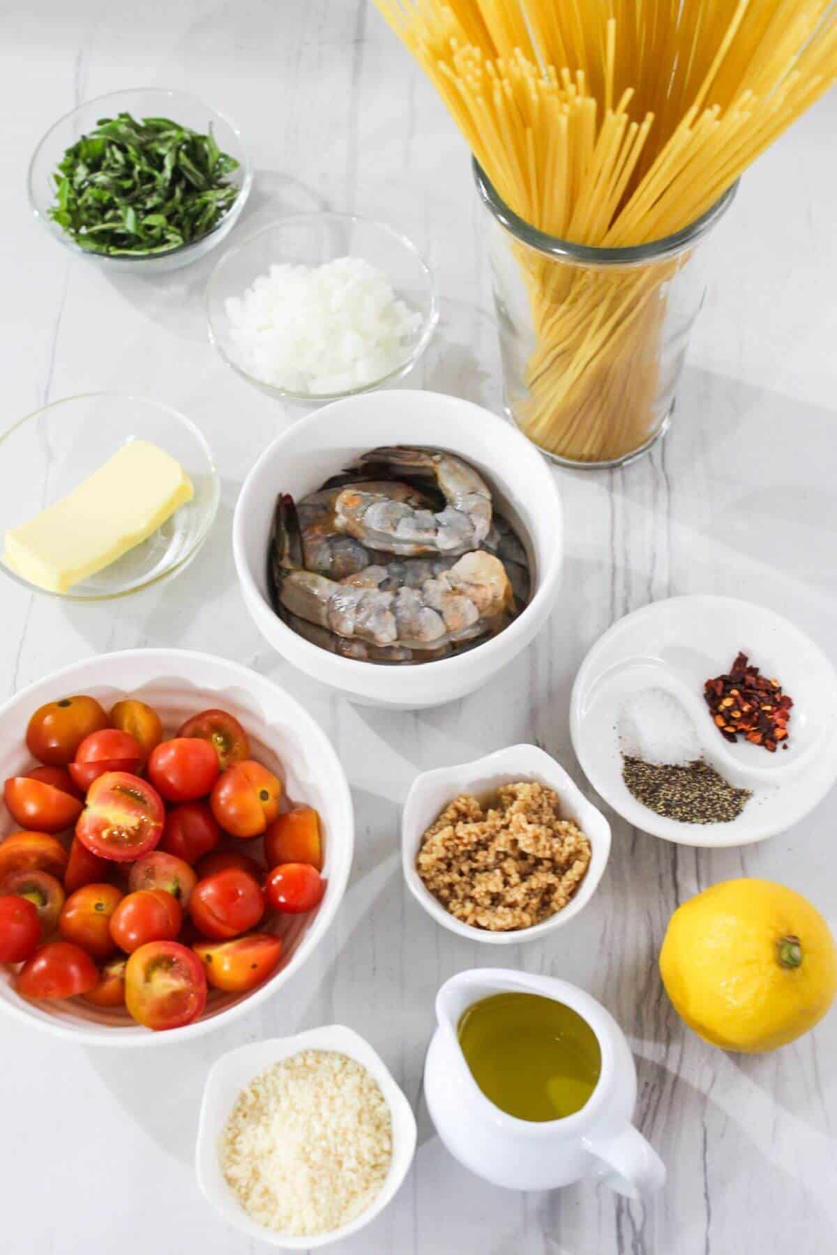 Ingredients for a pasta dish with shrimp, tomatoes and basil.