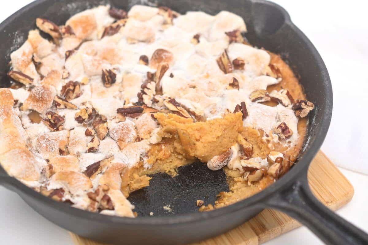 A skillet with sweet potato casserole and pecans.