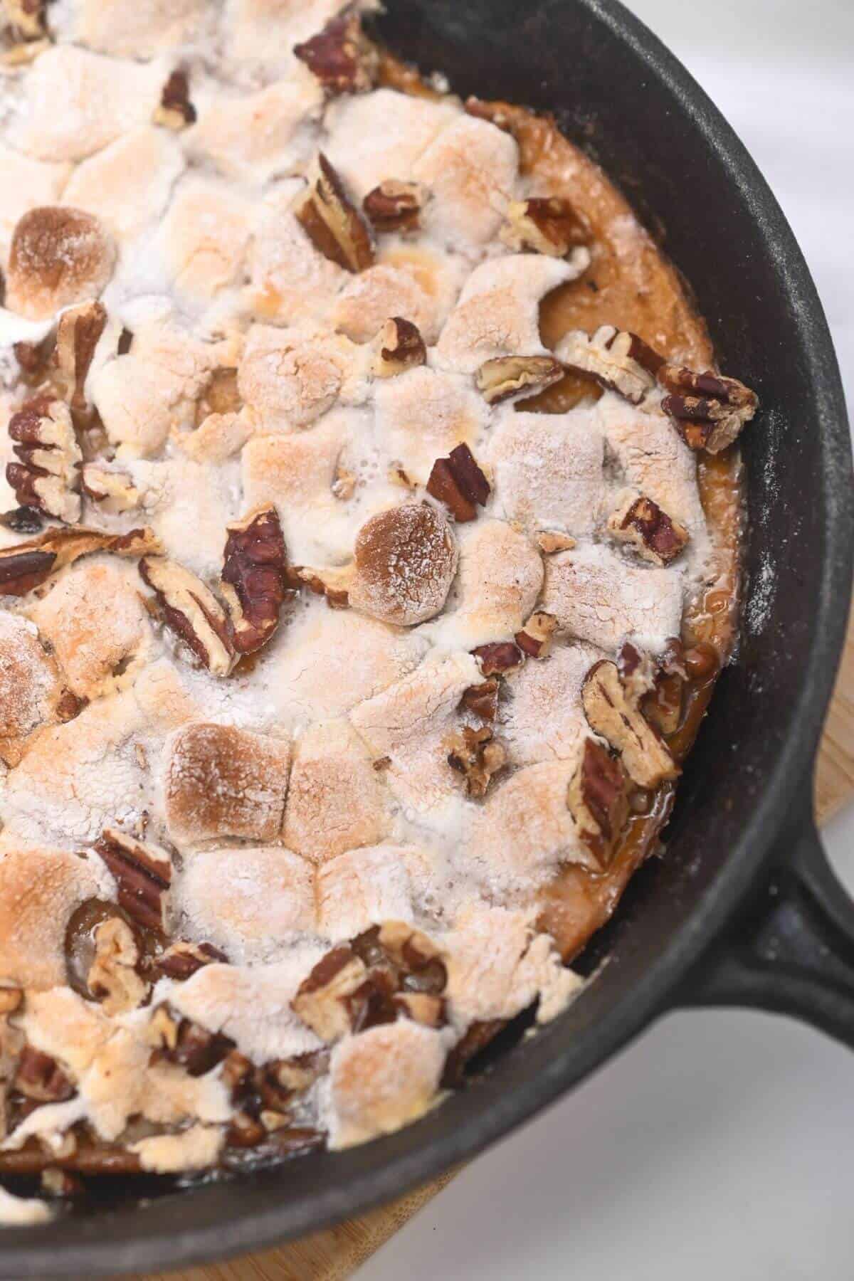 A skillet filled with sweet potato casserole and pecans.