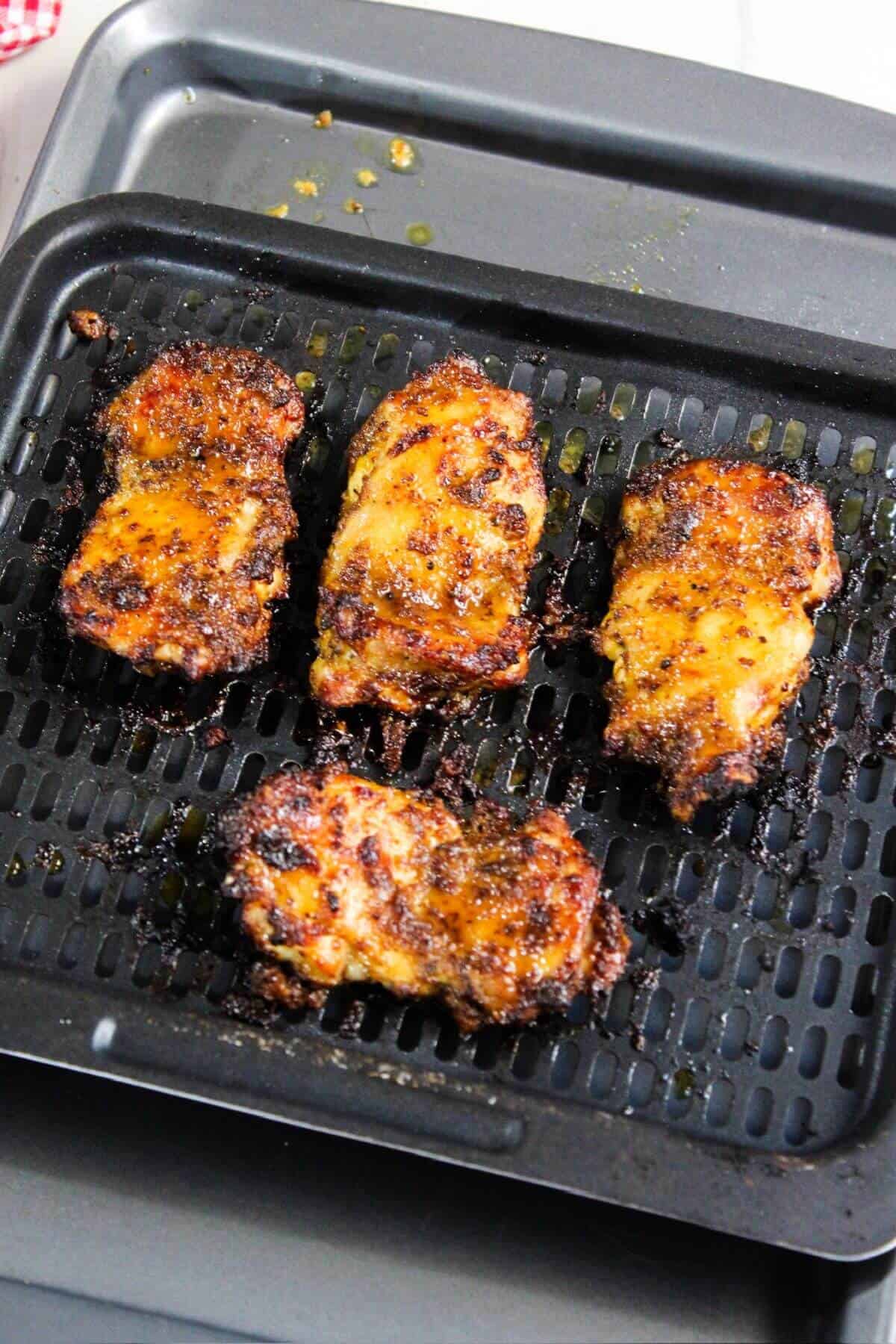 Air fryer boneless chicken thighs on an air fryer sheet.