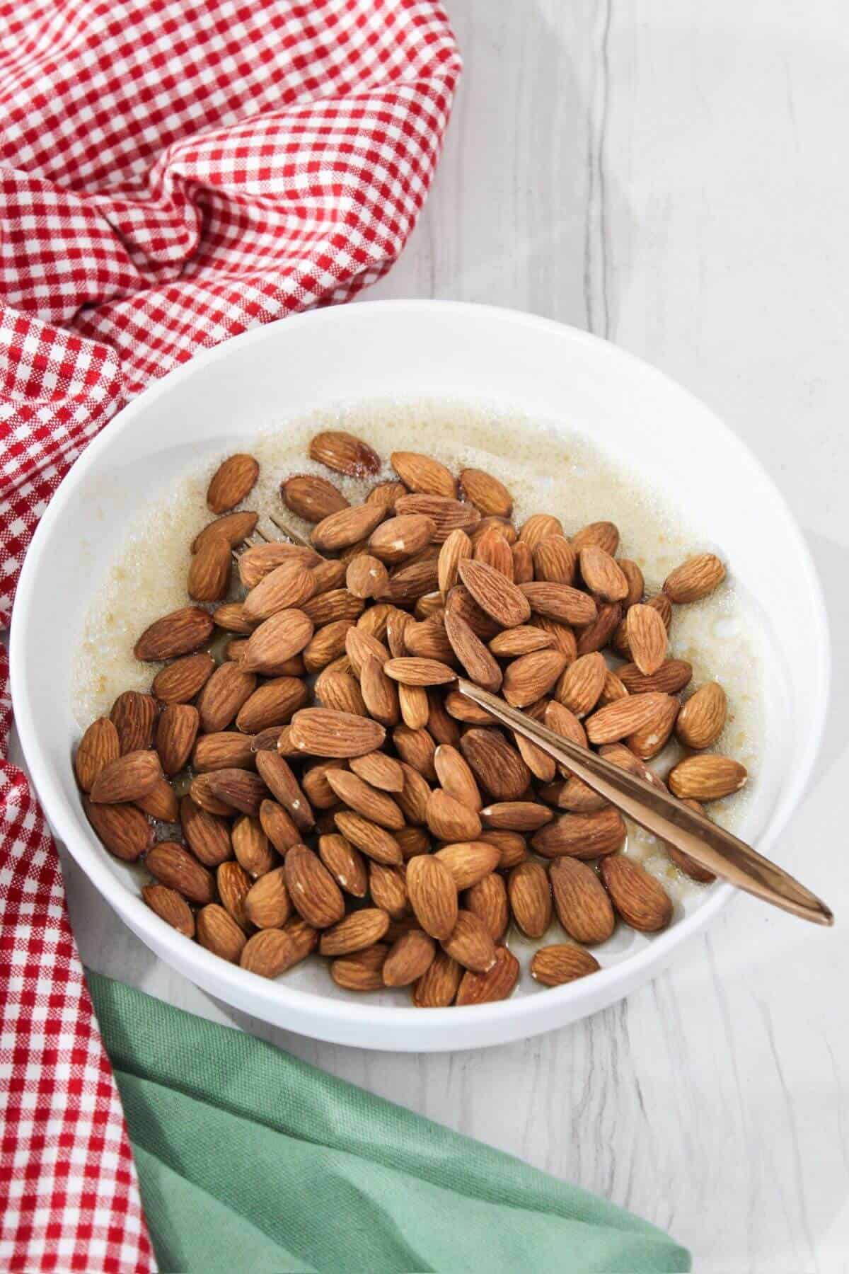 Almonds in a bowl on a white wooden table.