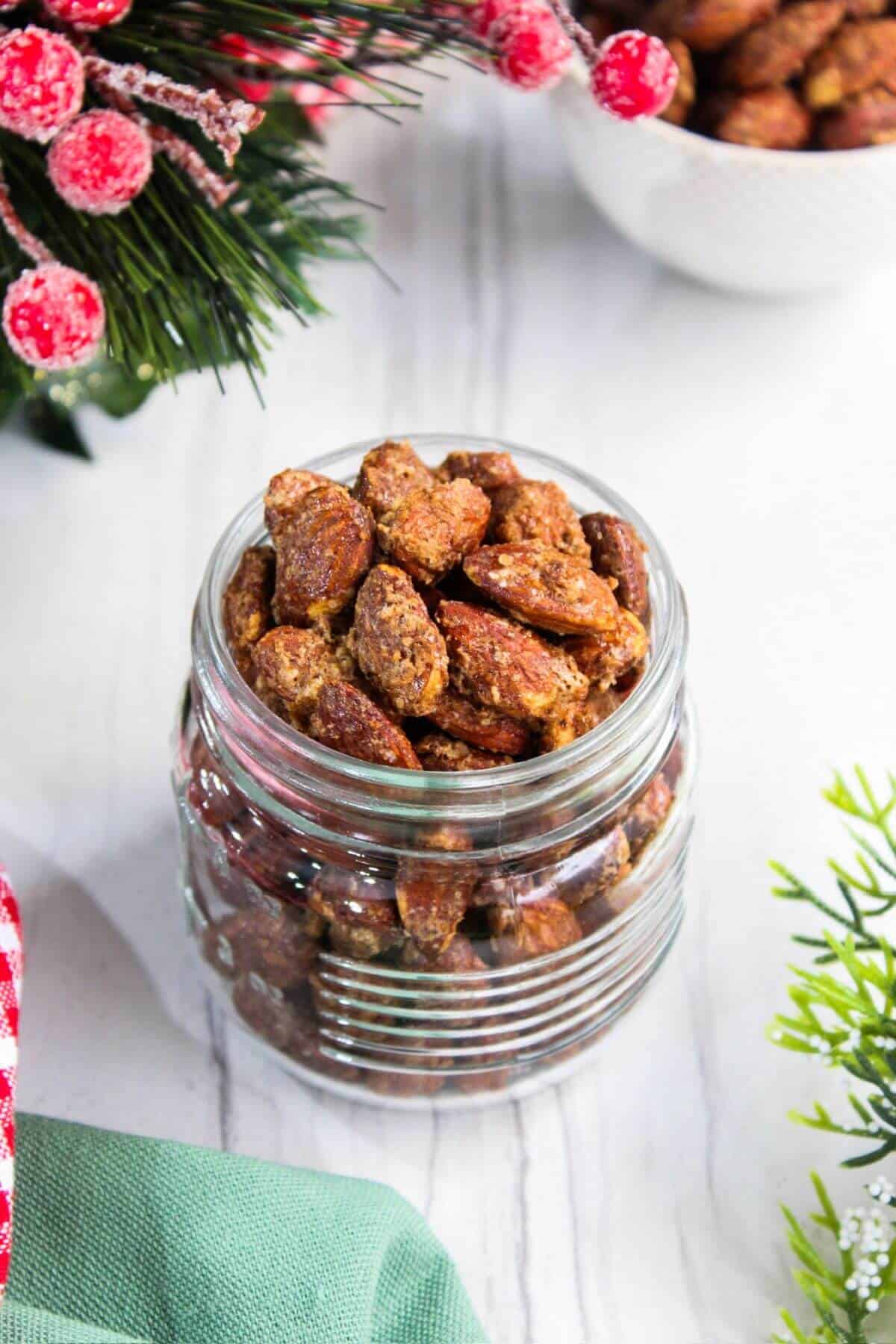 Candied almonds in a jar on a white table.