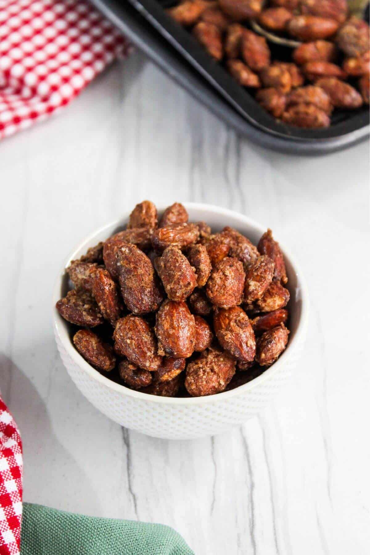Air fryer candied almonds in a white bowl with a red and white checkered tablecloth.