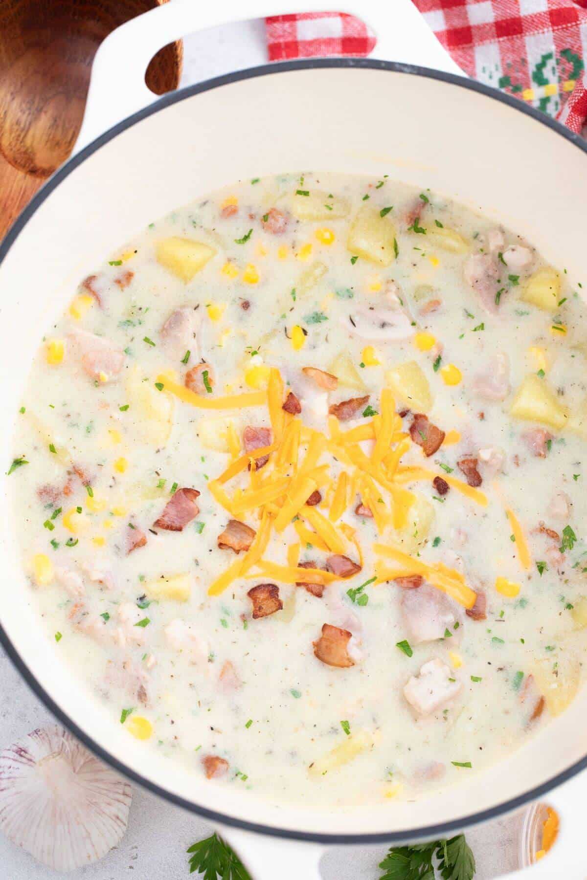 Corn chowder with chicken and cheese in a pan.