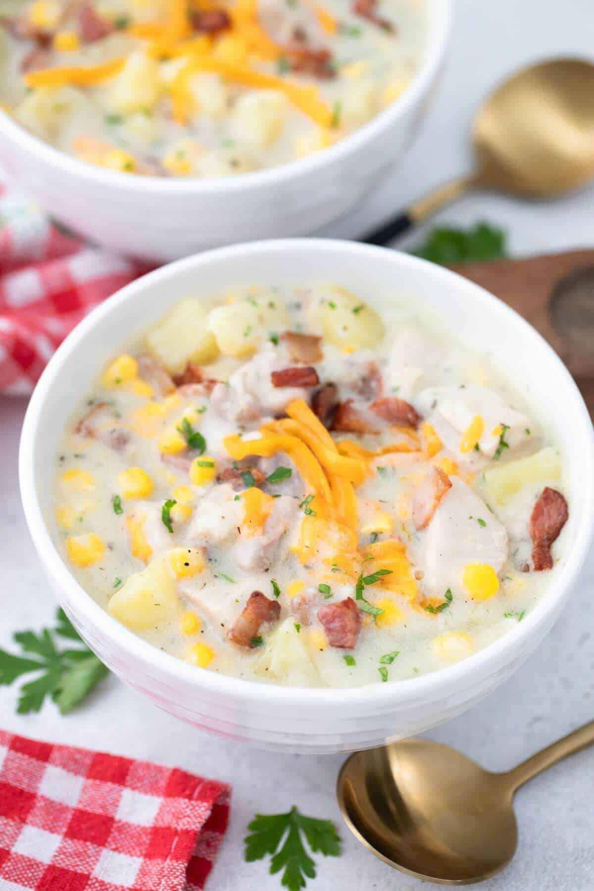 Two bowls of chicken chowder with potatoes and cheese.