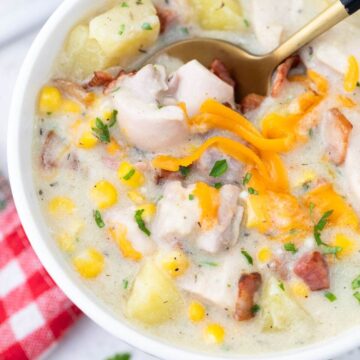 Chicken and corn chowder in a white bowl with a gold spoon.