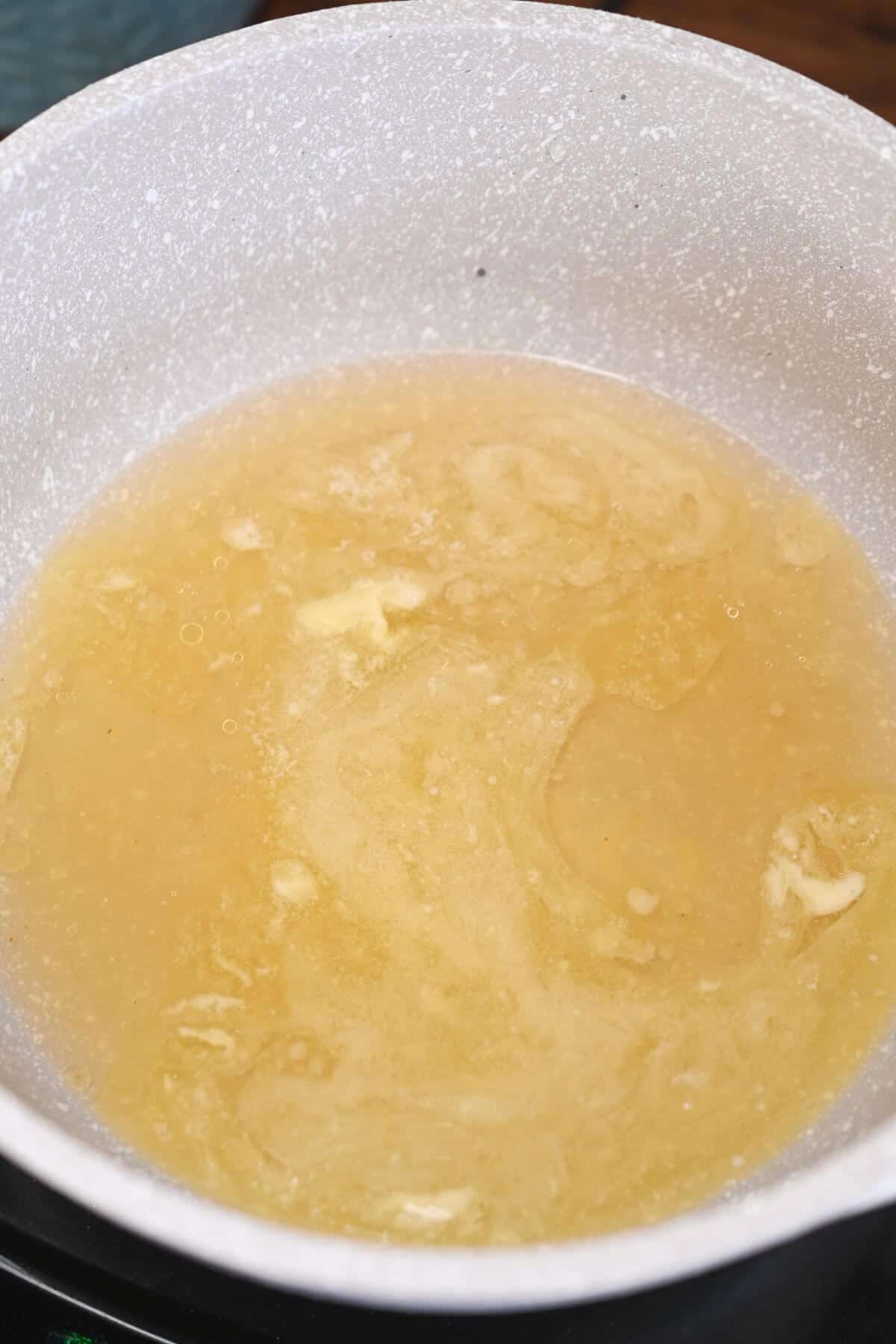 A frying pan with a chicken broth and butter mixture in it.