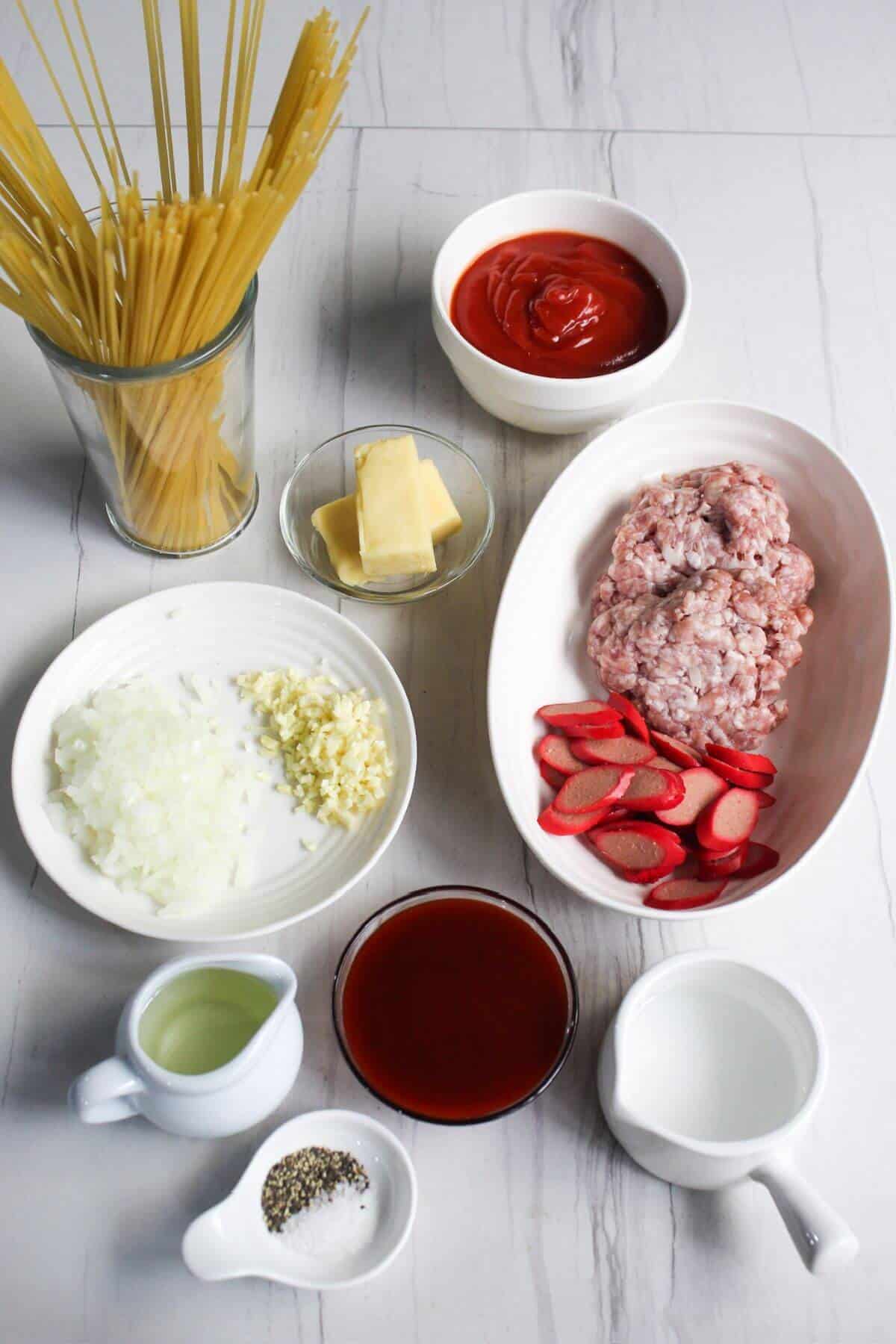 Ingredients for Filipino spaghetti in white bowls on a white background.