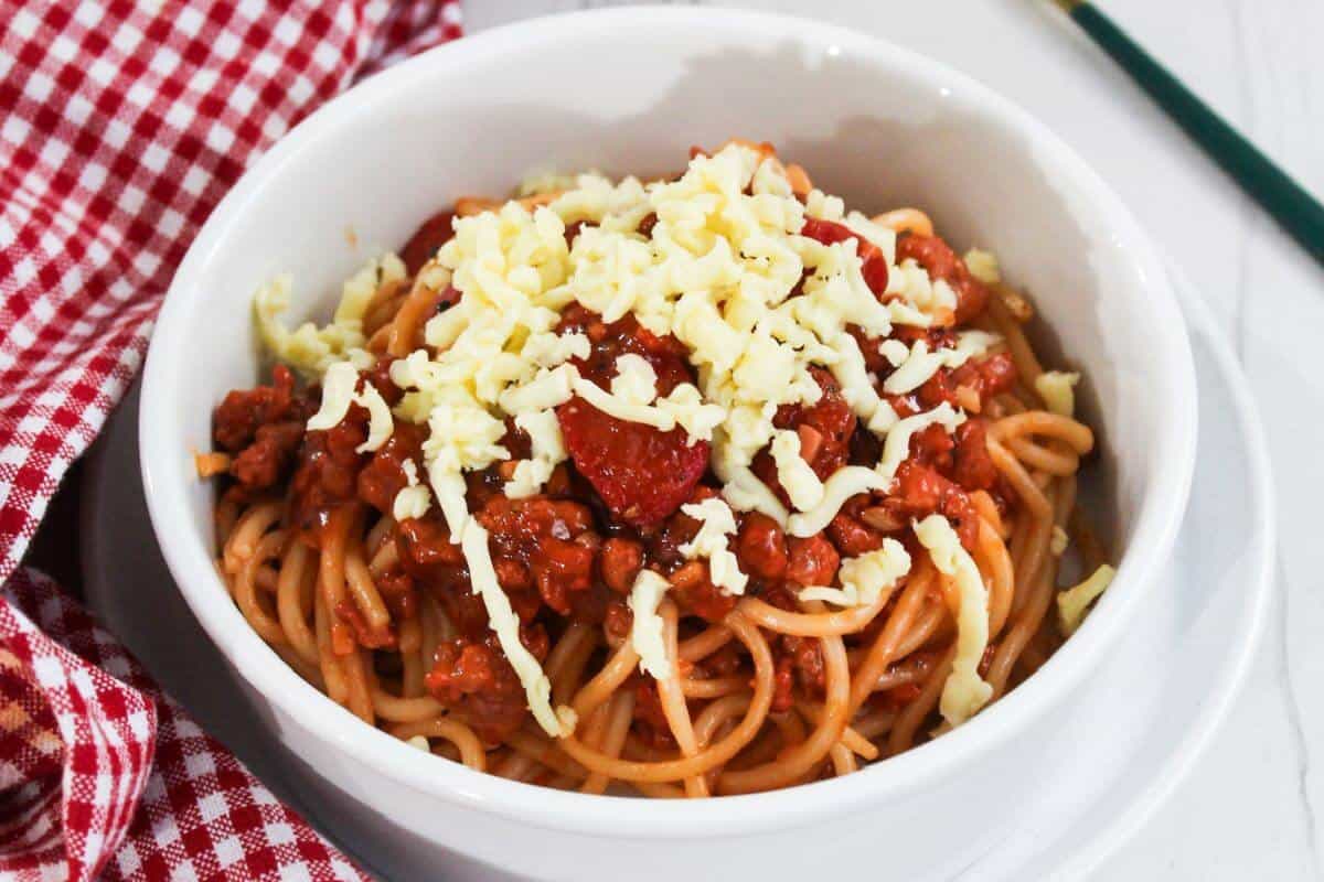 A bowl of spaghetti with meat sauce and cheese.