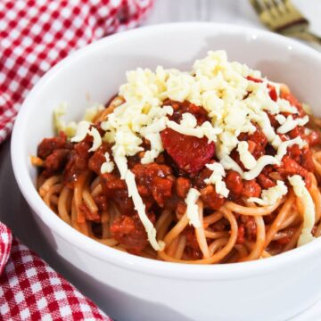 A bowl of Filipino spaghetti with meat sauce and cheese.