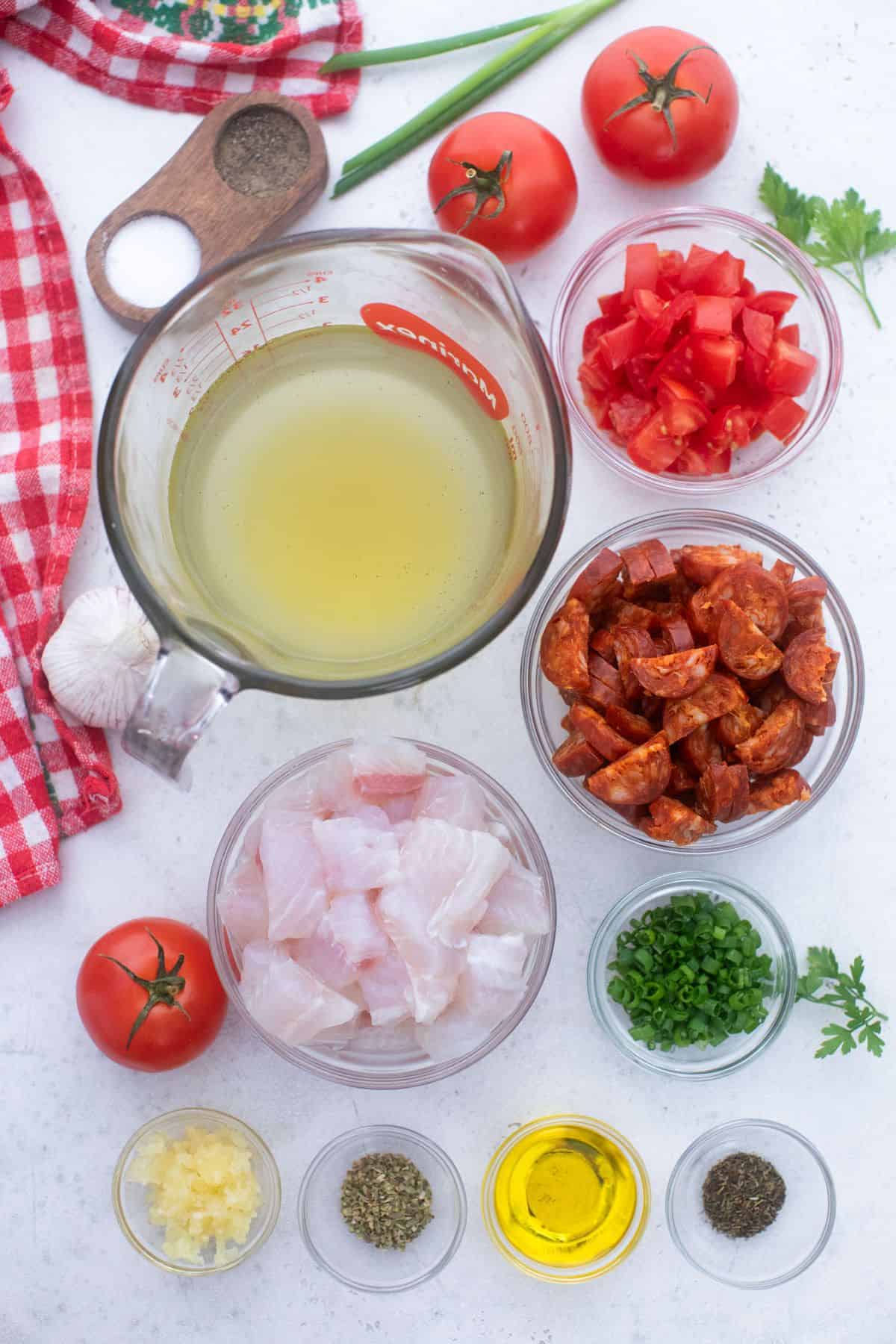 A bowl of ingredients for a chicken salad with tomatoes and herbs.