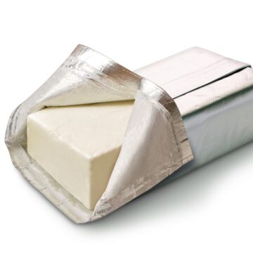A piece of cream cheese wrapped in foil out to soften.