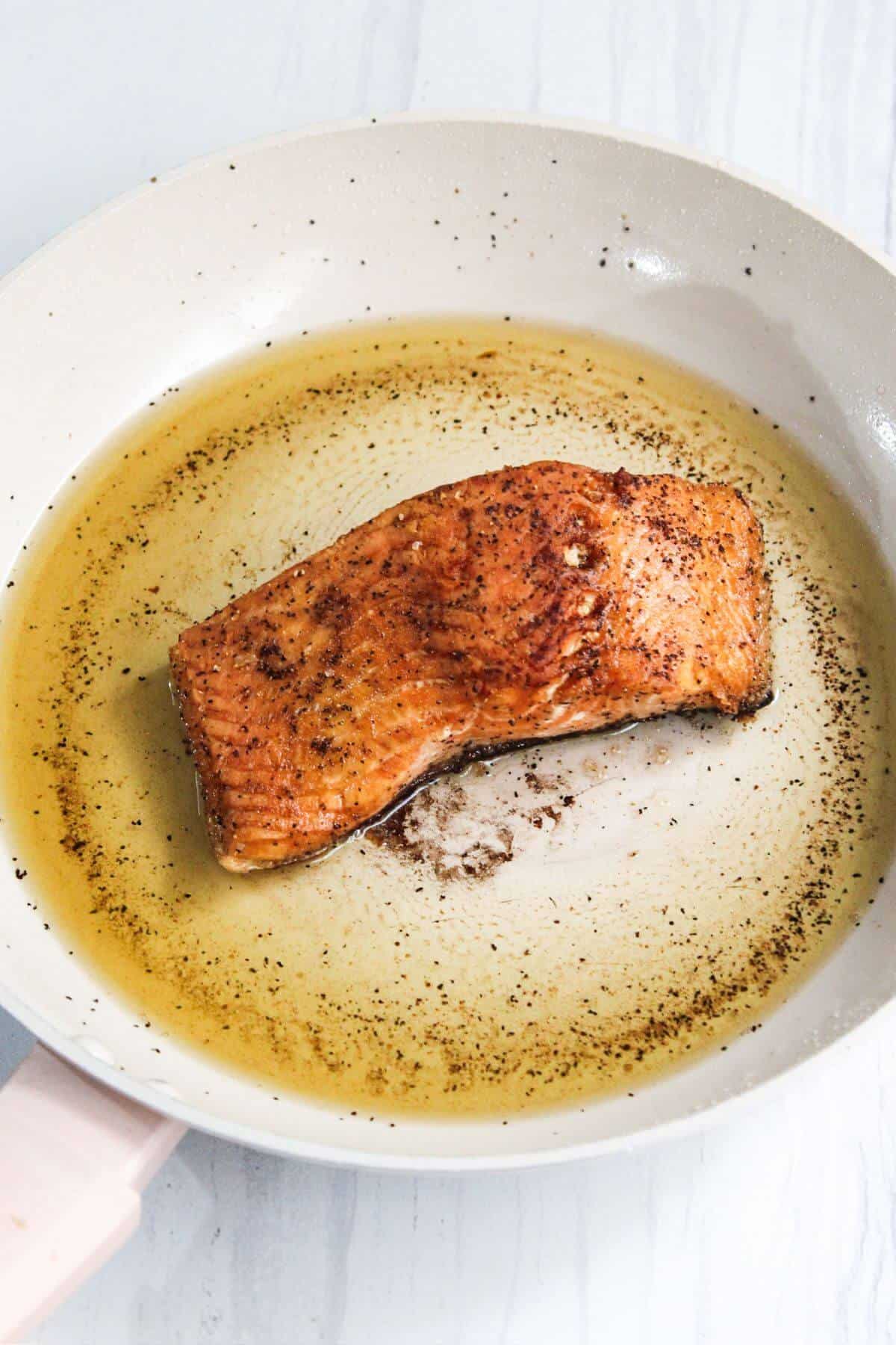 A salmon fillet in a frying pan.