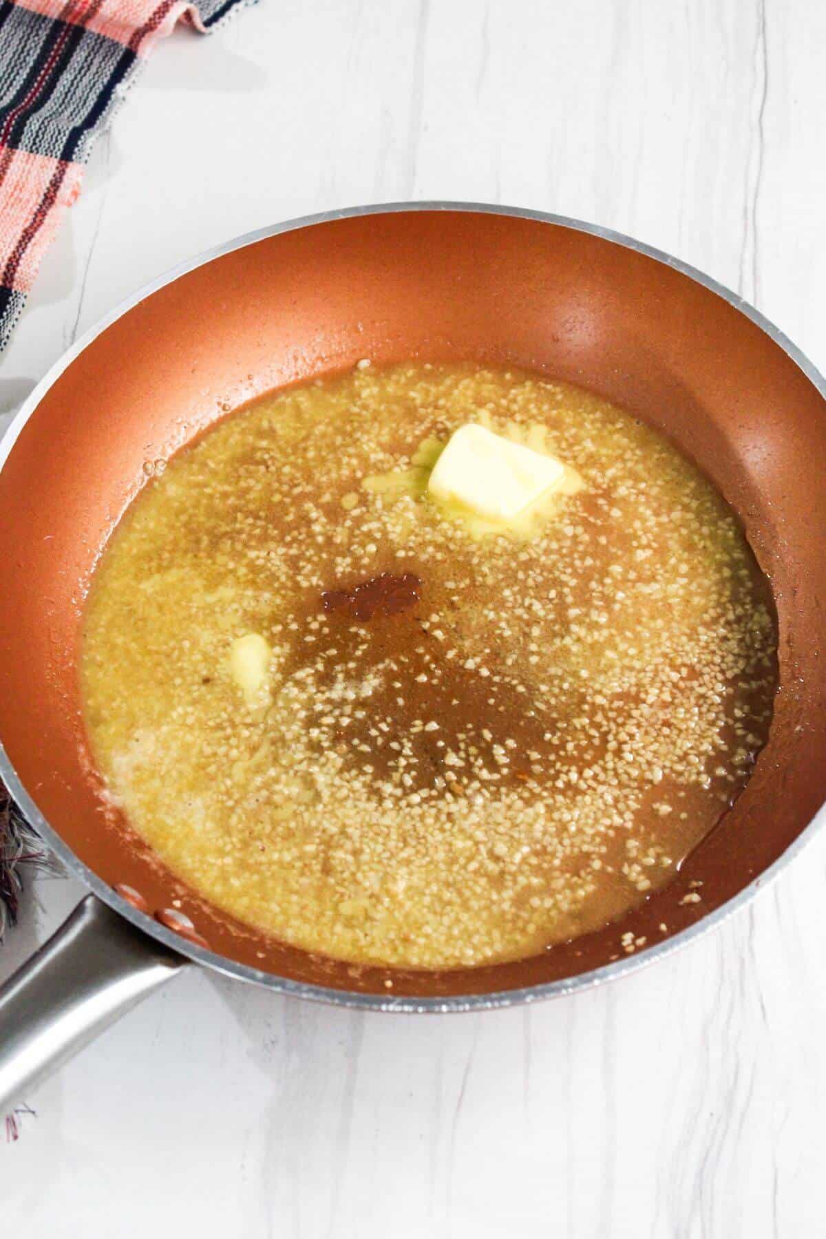 A frying pan with lemon butter sauce in it.
