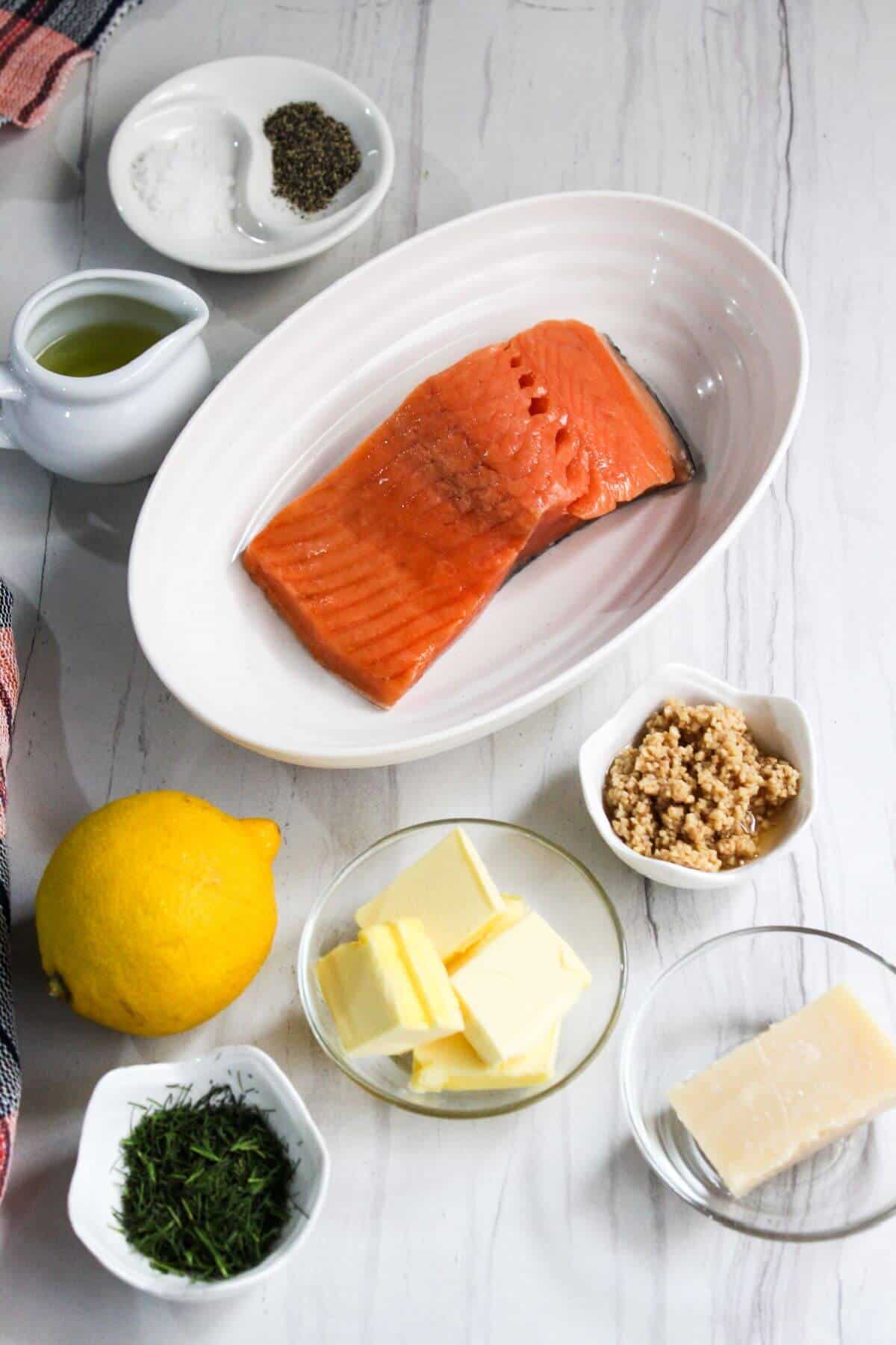 Salmon, lemon, butter and other ingredients on a white table.