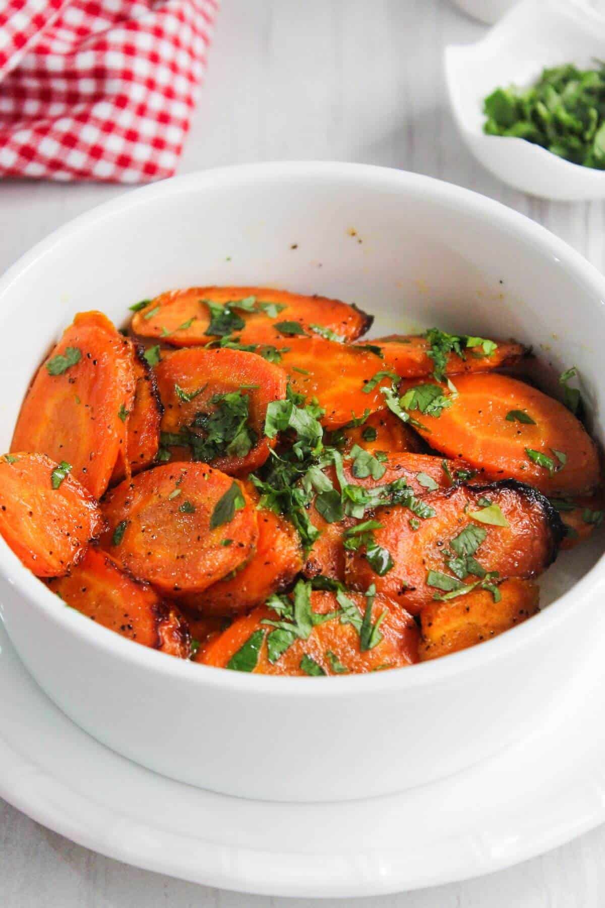 Maple glazed carrots in a white bowl with parsley.