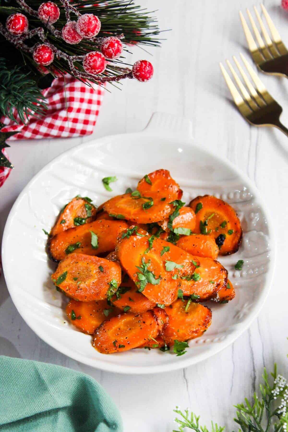 Maple glazed carrots with parsley on a white plate.