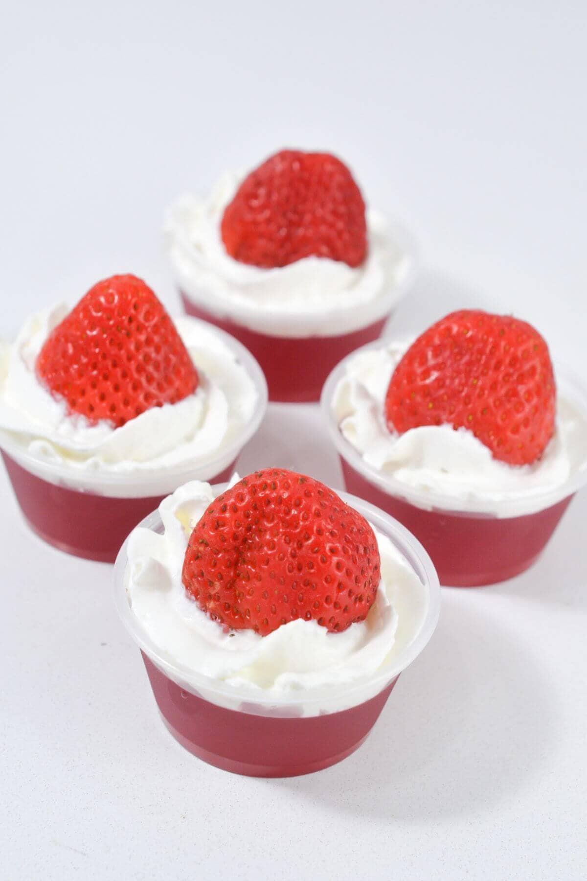 Jello cups with whipped cream and strawberries.
