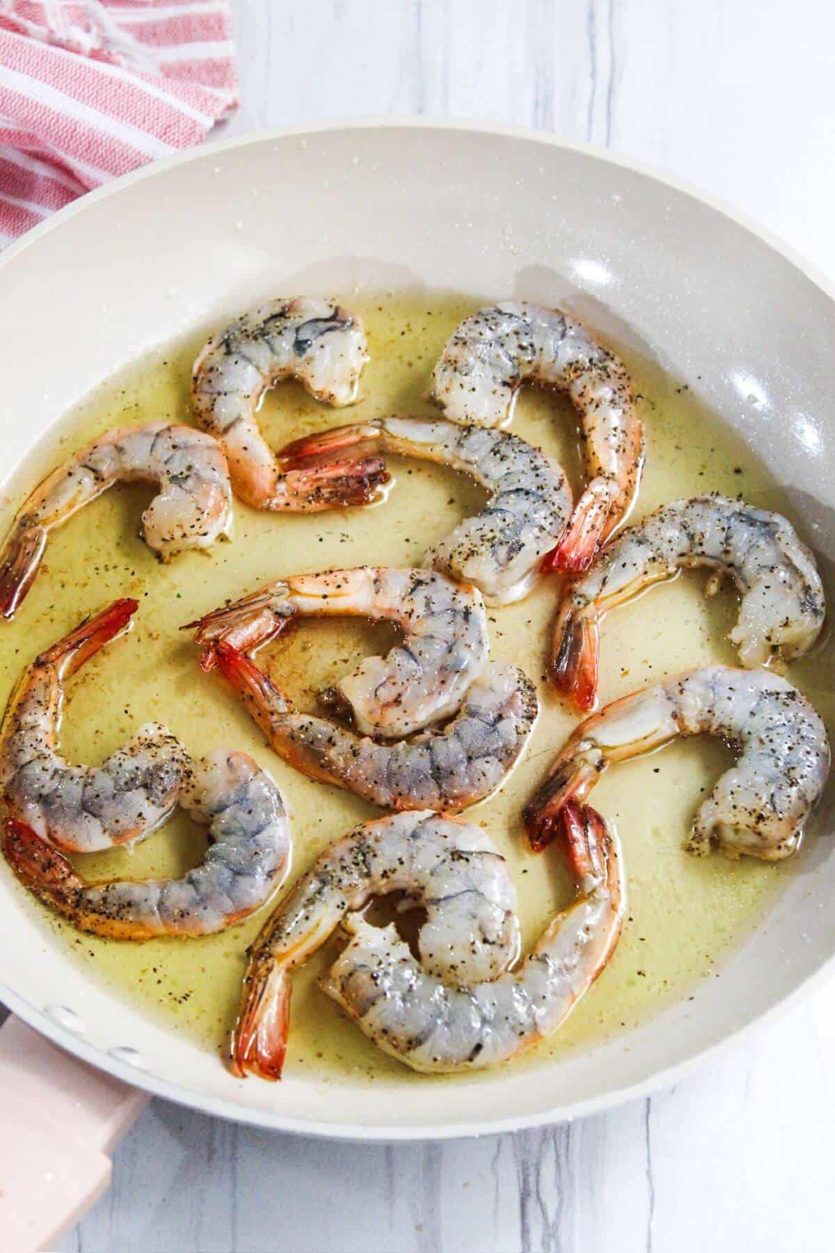 A frying pan with shrimp in it.