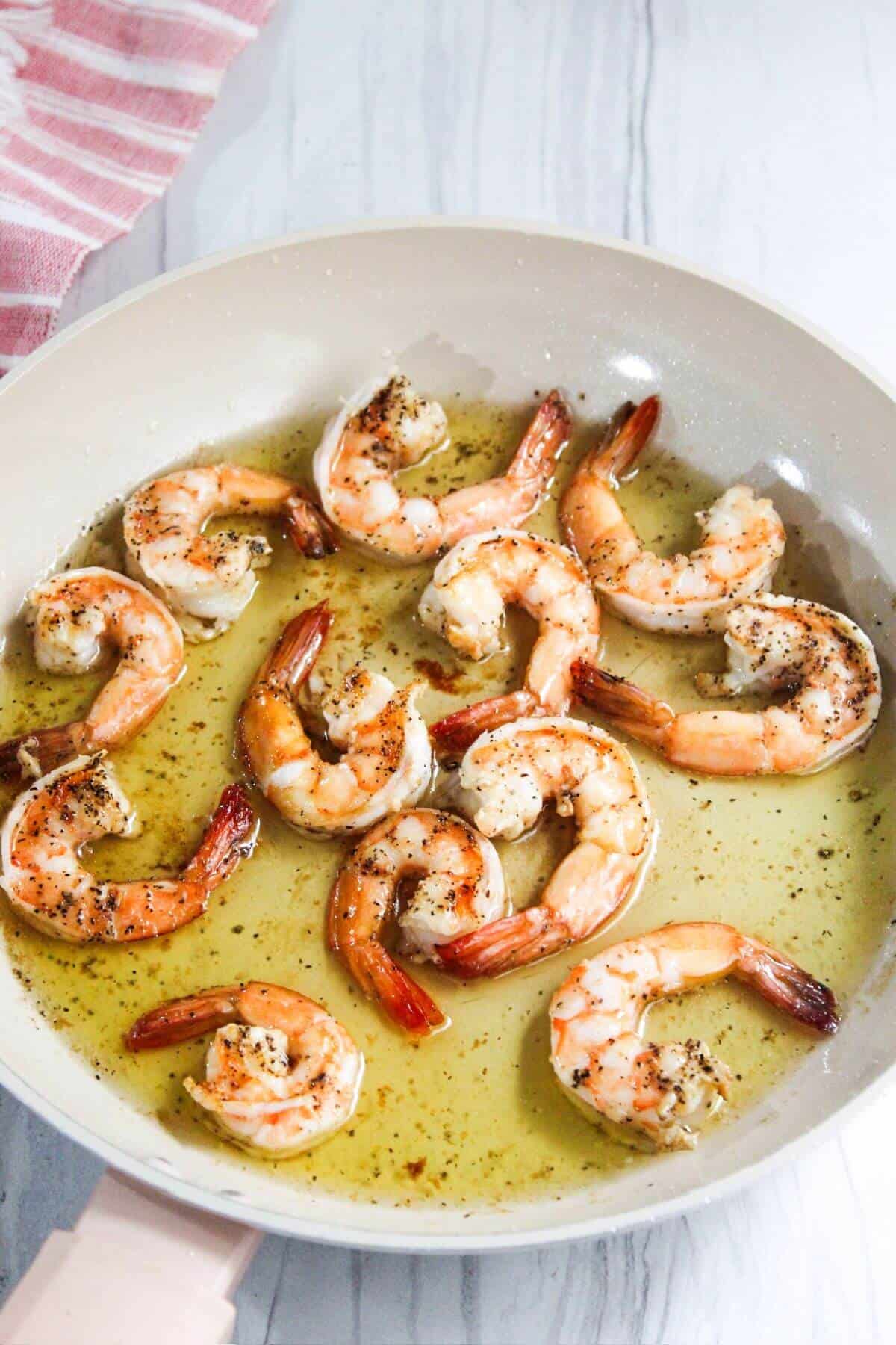 Shrimp in a frying pan with olive oil.