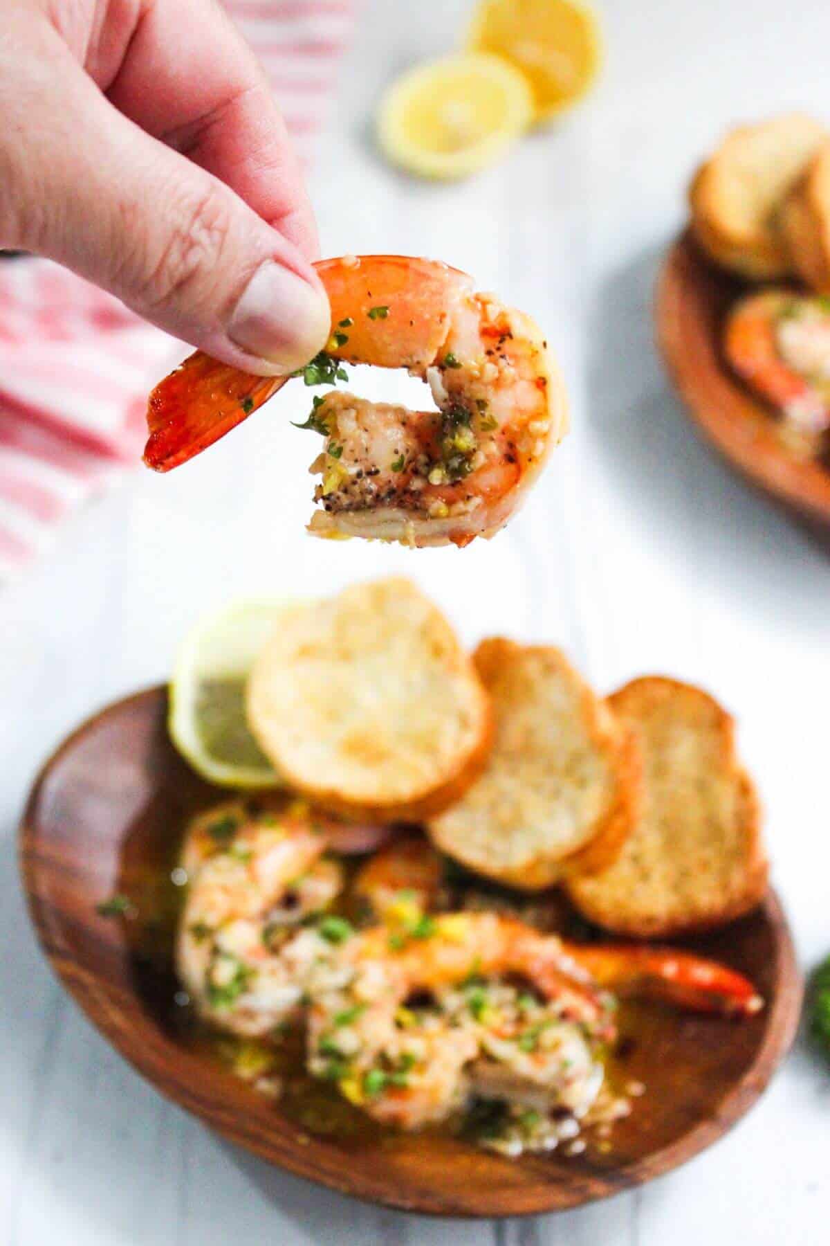 A person is grabbing a shrimp from a plate.