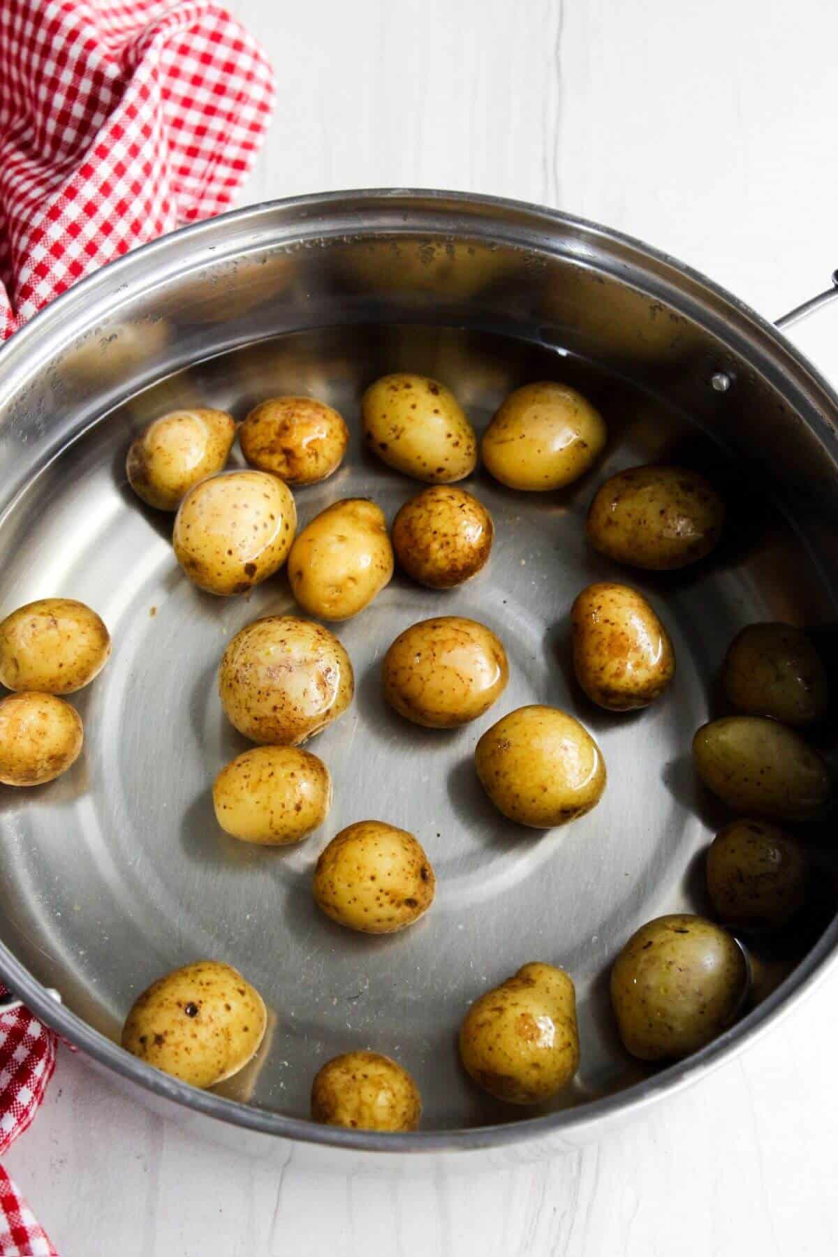 Potatoes in a pan with a red and white checkered cloth.