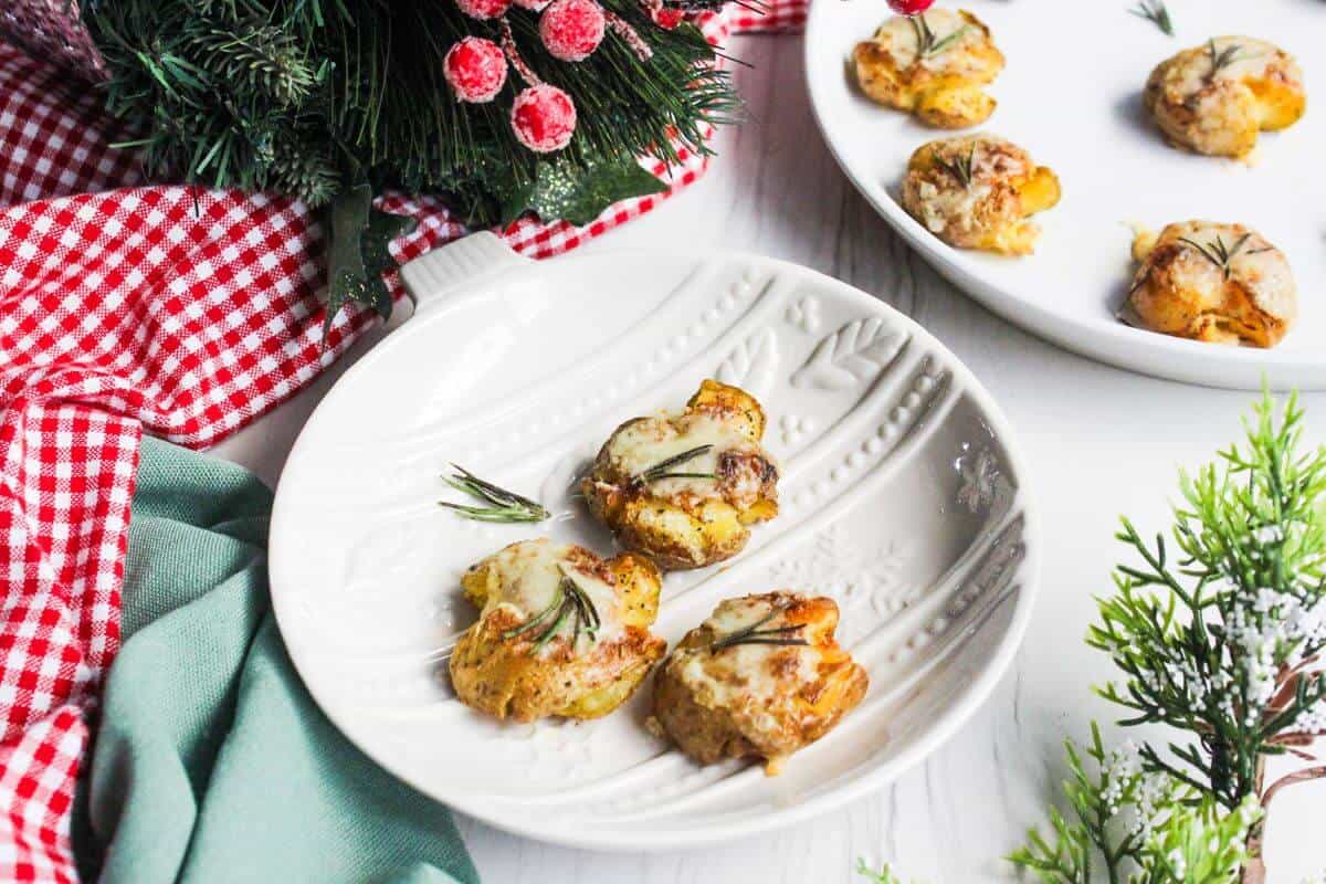 Cheesy smashed potatoes on a plate next to a Christmas sprig.