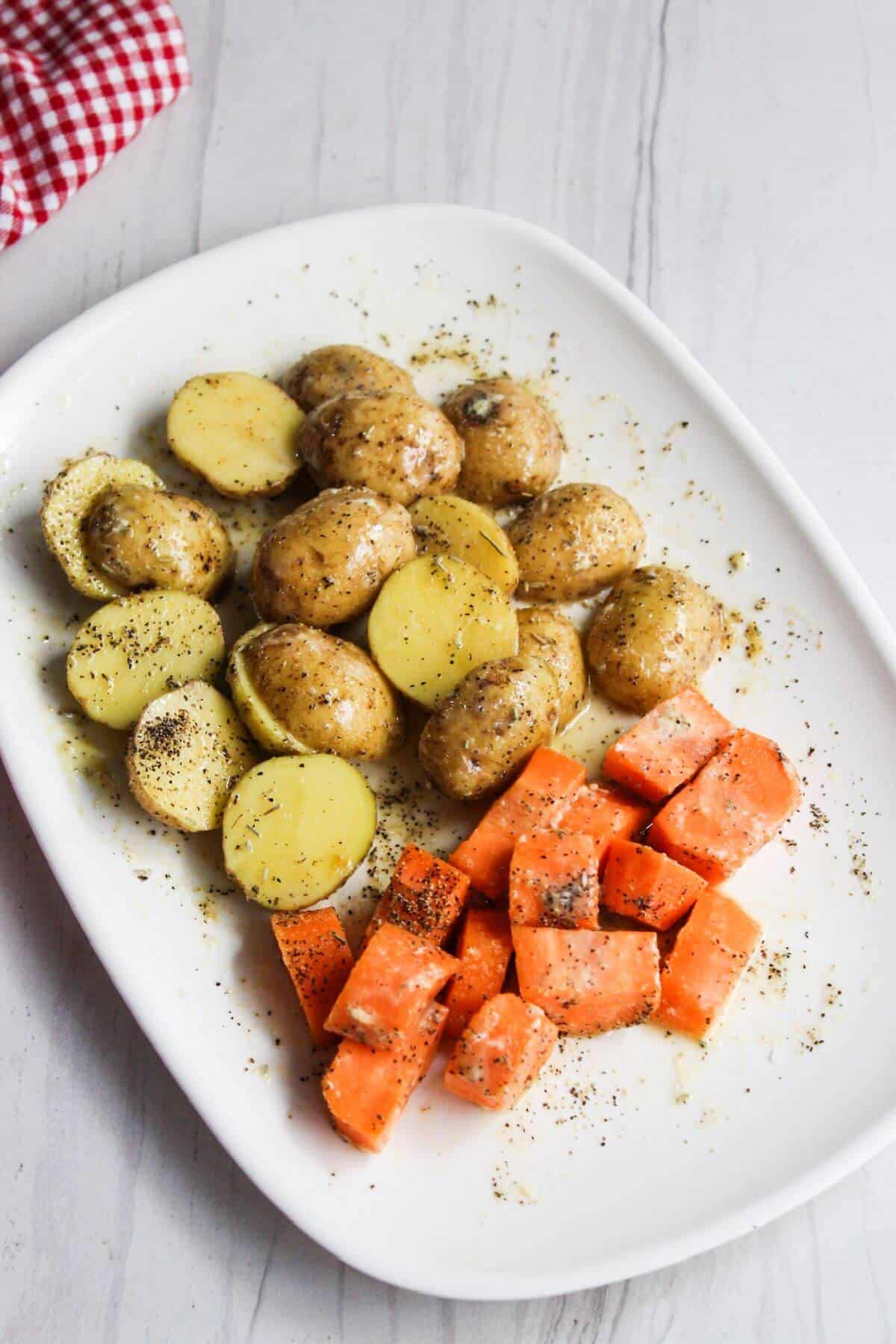 Seasoned potatoes and carrots on a white plate.