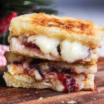 A stack of brie grilled cheese with cranberry sauce.