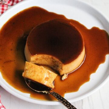 A leche flan dessert with caramel sauce and a spoon on a plate.