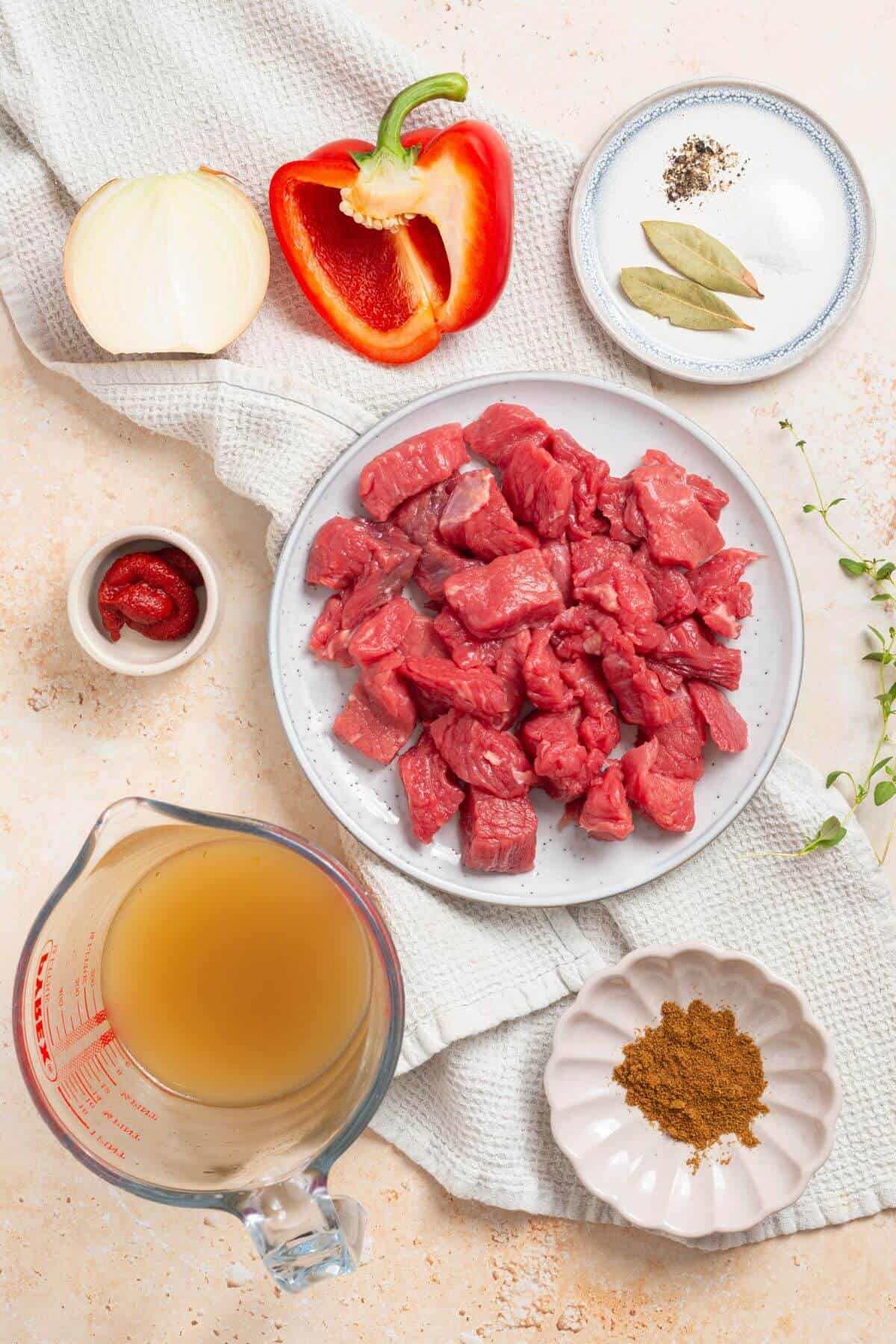 The ingredients for a pepper steak dish are on a table.