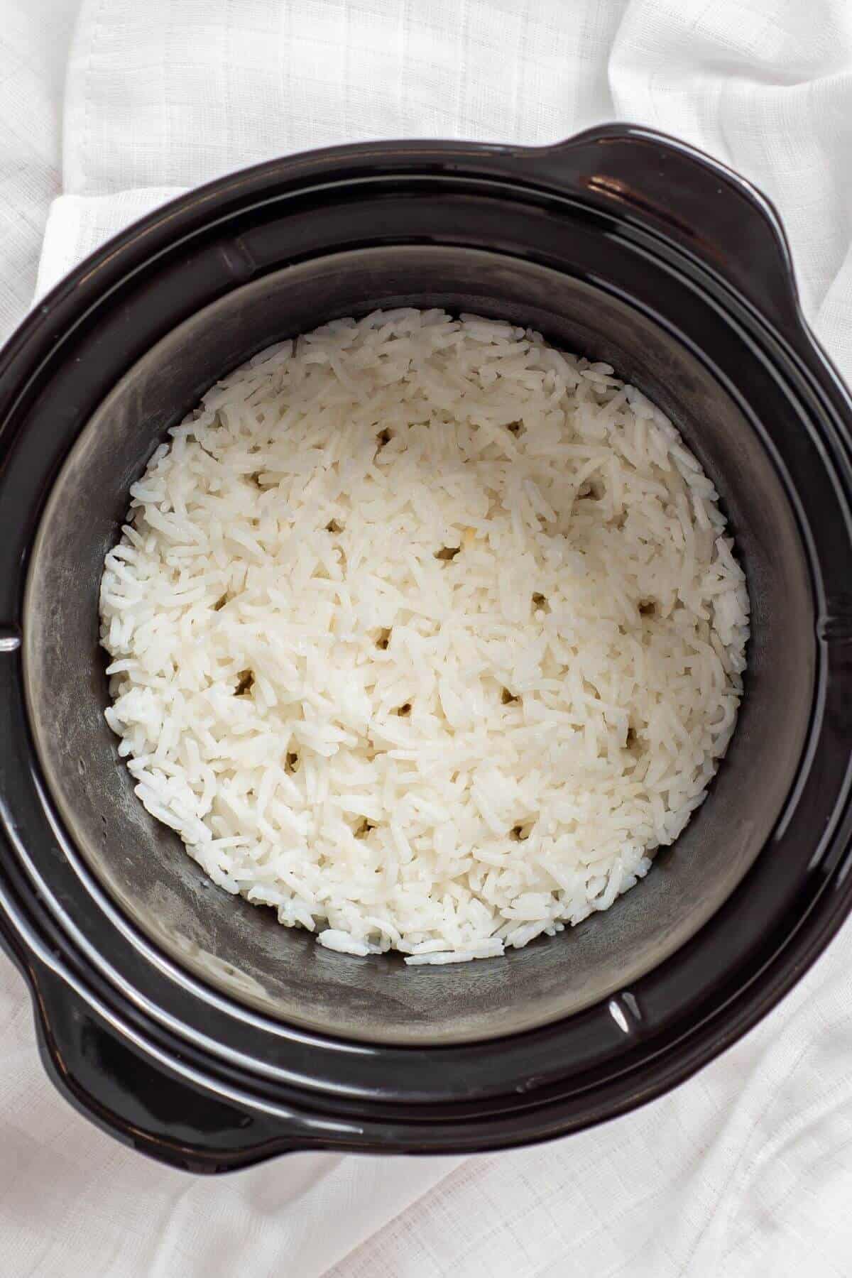 A crock pot filled with rice on top of a white towel.