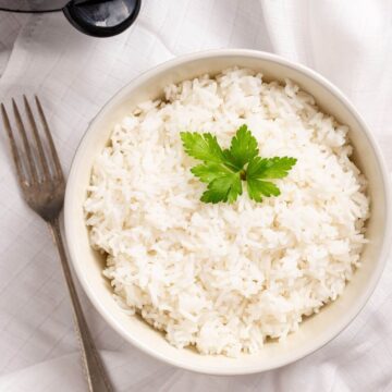White rice in a bowl next to a fork.