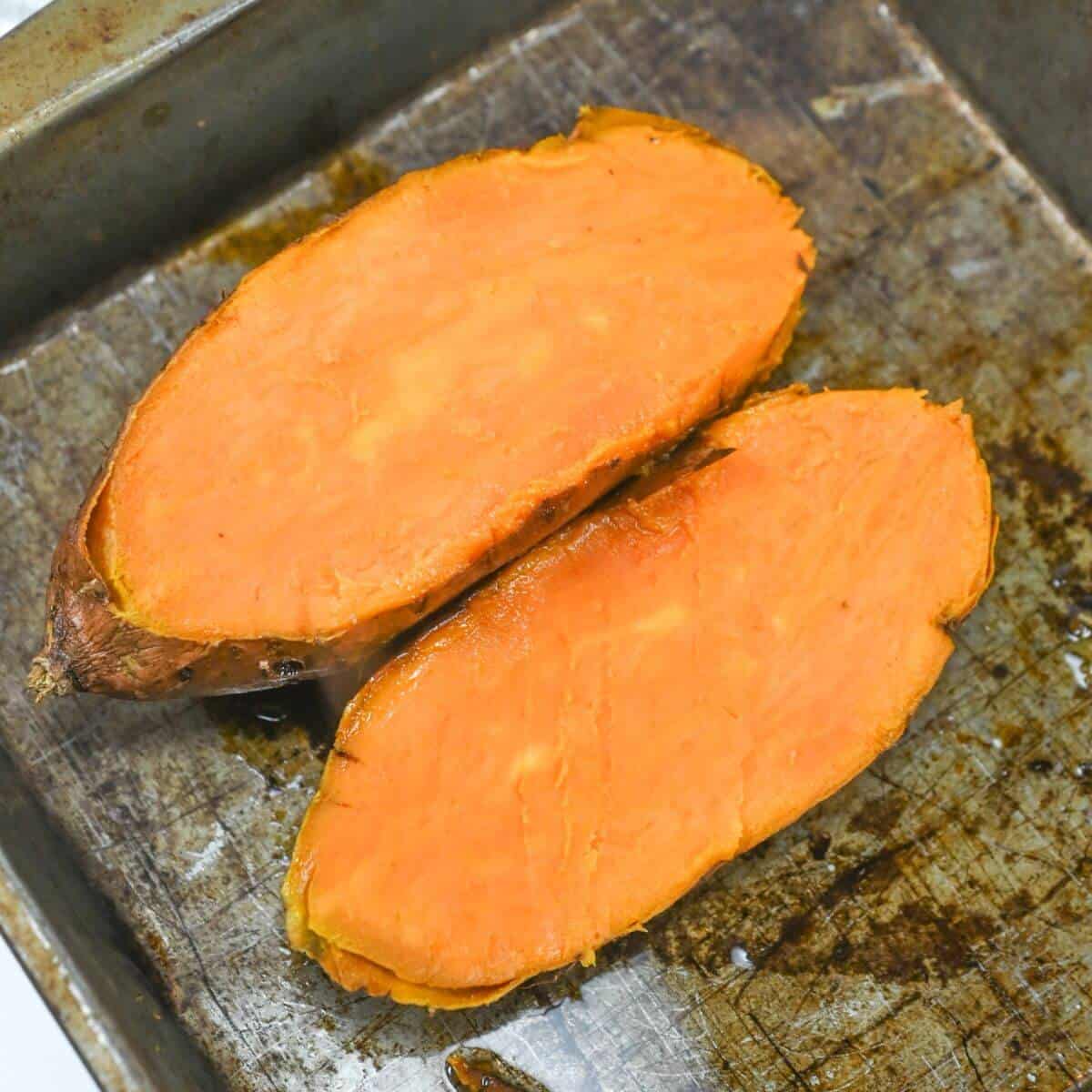 Two sliced sweet potato halves on a baking sheet.