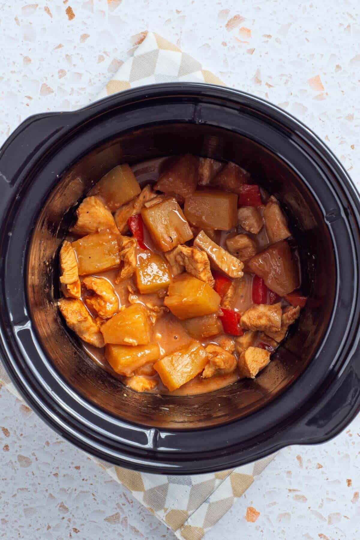 A crock pot filled with chicken and pineapple.