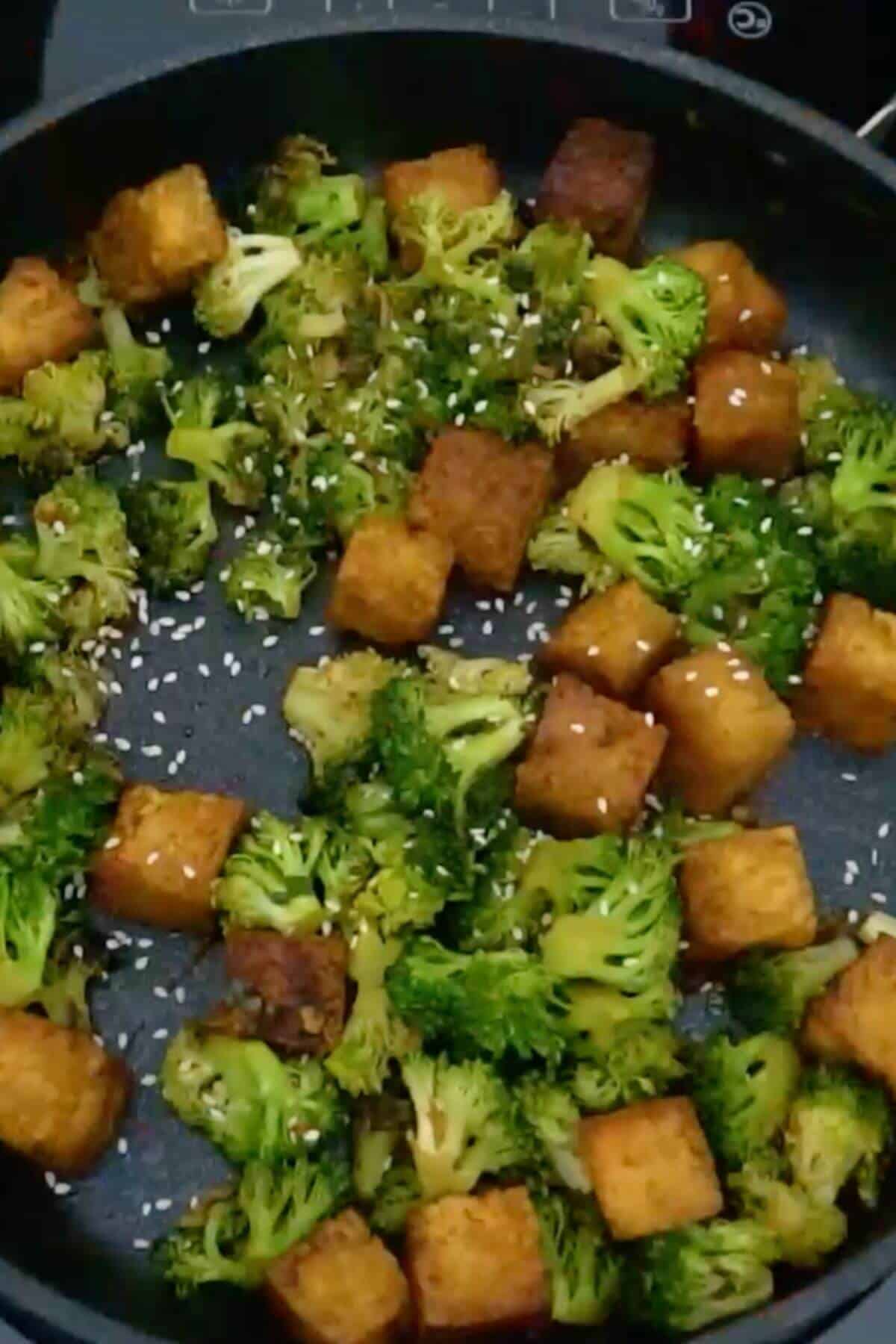 A frying pan with broccoli and tofu.