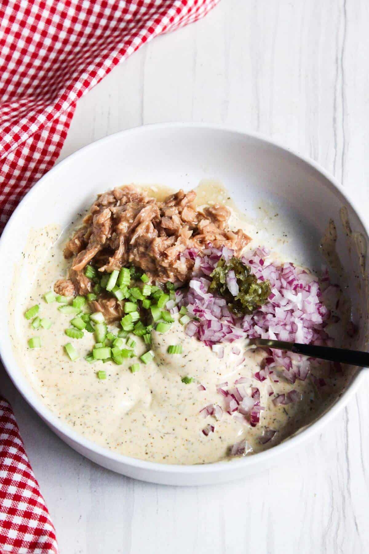 Tuna, onions and relish added to mayonnaise mixture in bowl.