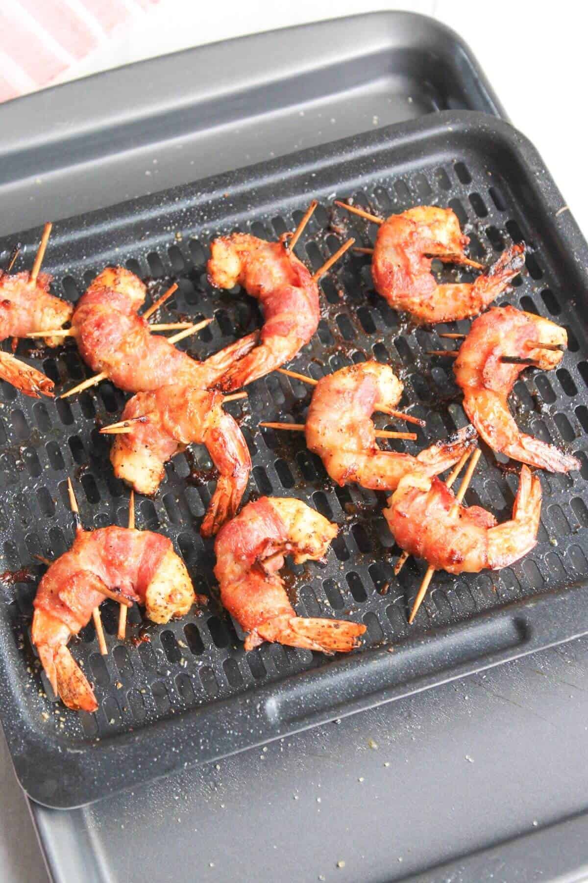 Bacon wrapped shrimp on an air fryer tray.