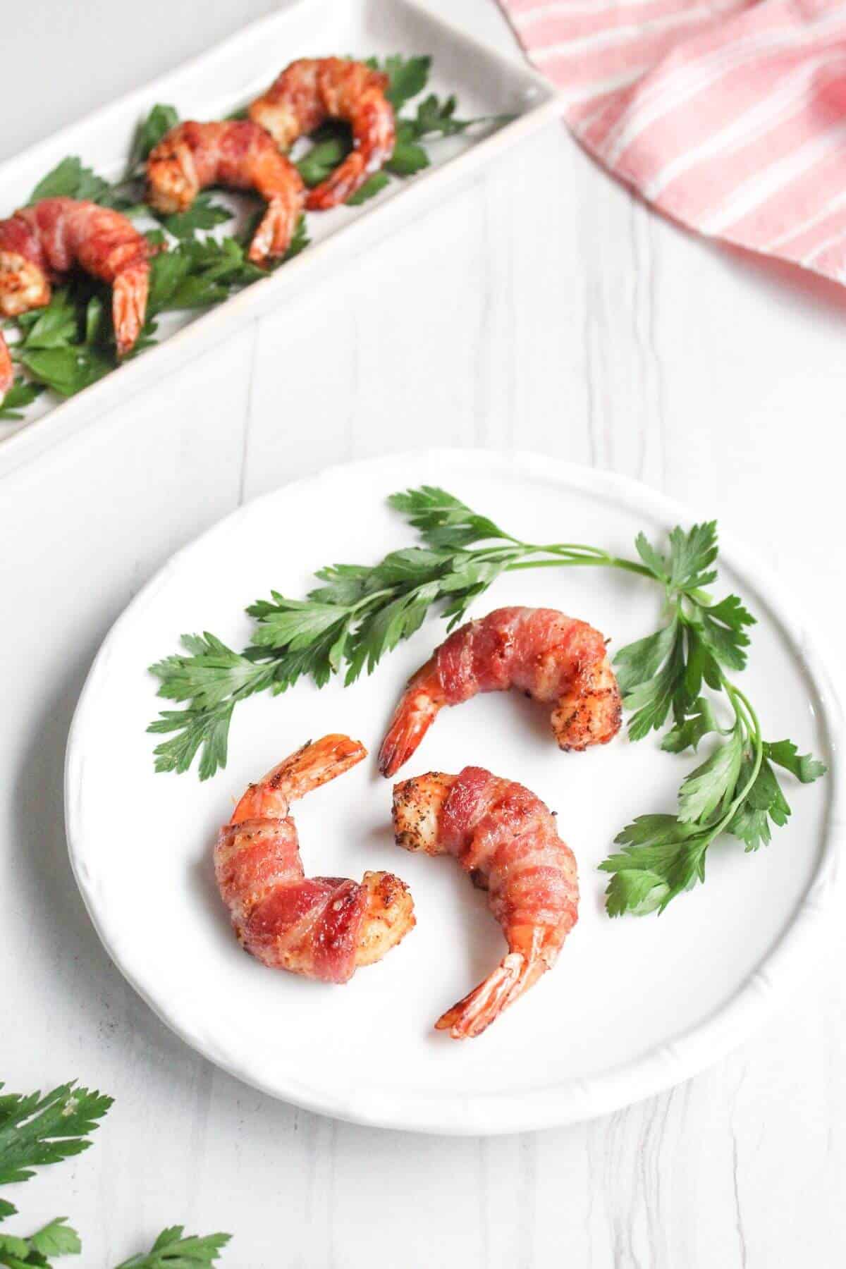 Bacon wrapped shrimp on a plate with parsley.