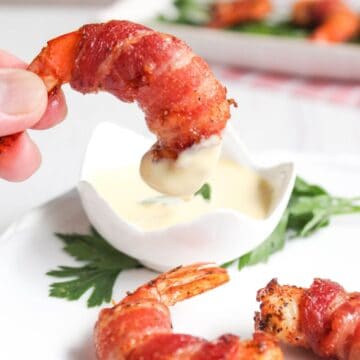 Bacon wrapped shrimp on a plate with dipping sauce.
