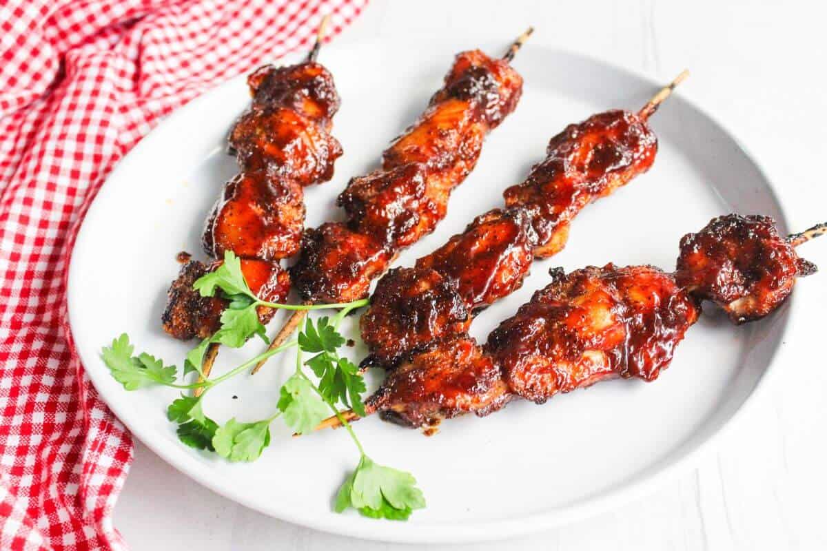 Bbq chicken skewers on a white plate.