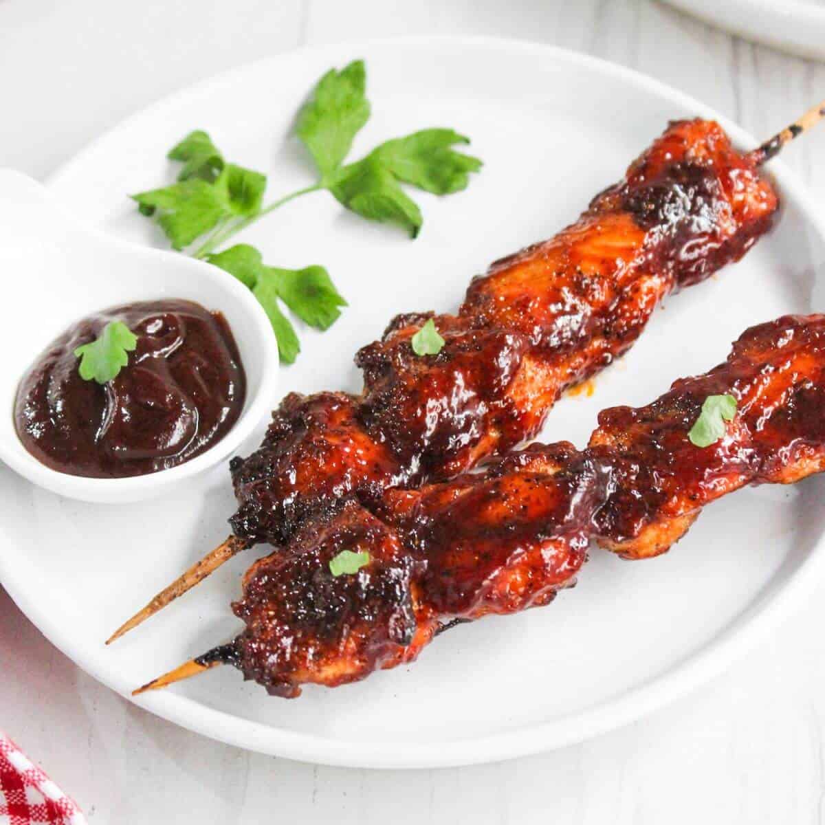 Chicken skewers drizzled with BBQ sauce, arranged on a plate.