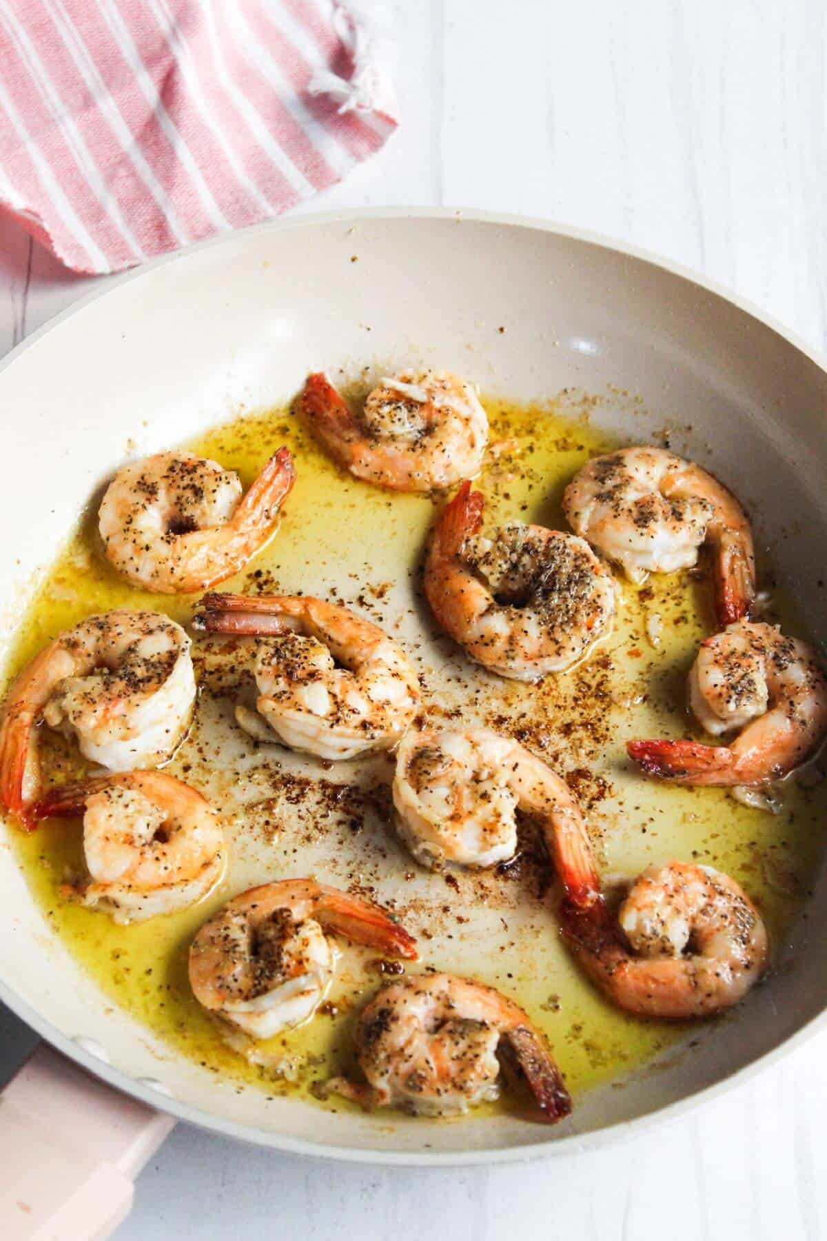 Shrimp in a frying pan with oil and spices.