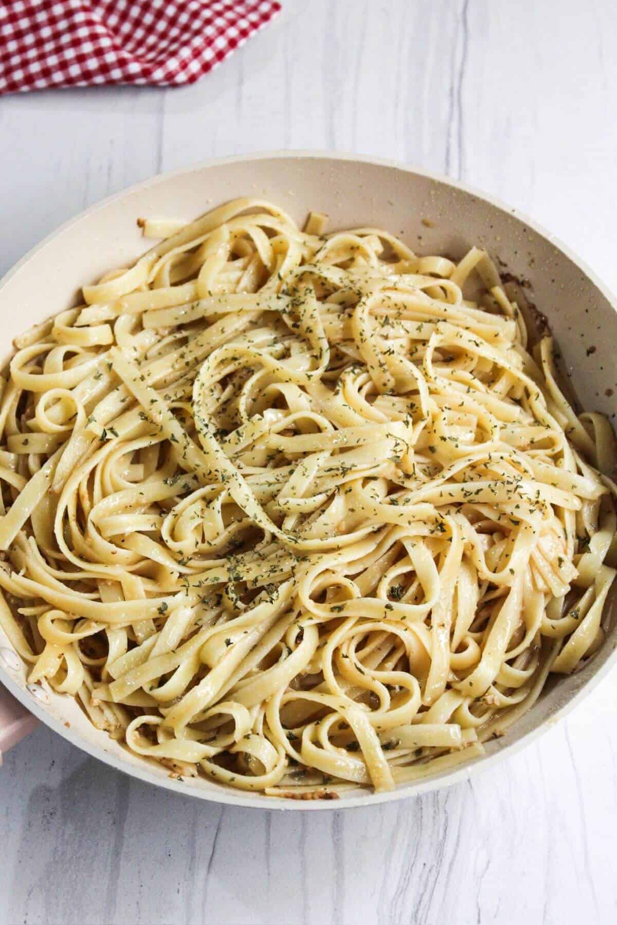 Flat pasta noodles in a pan on a white table.