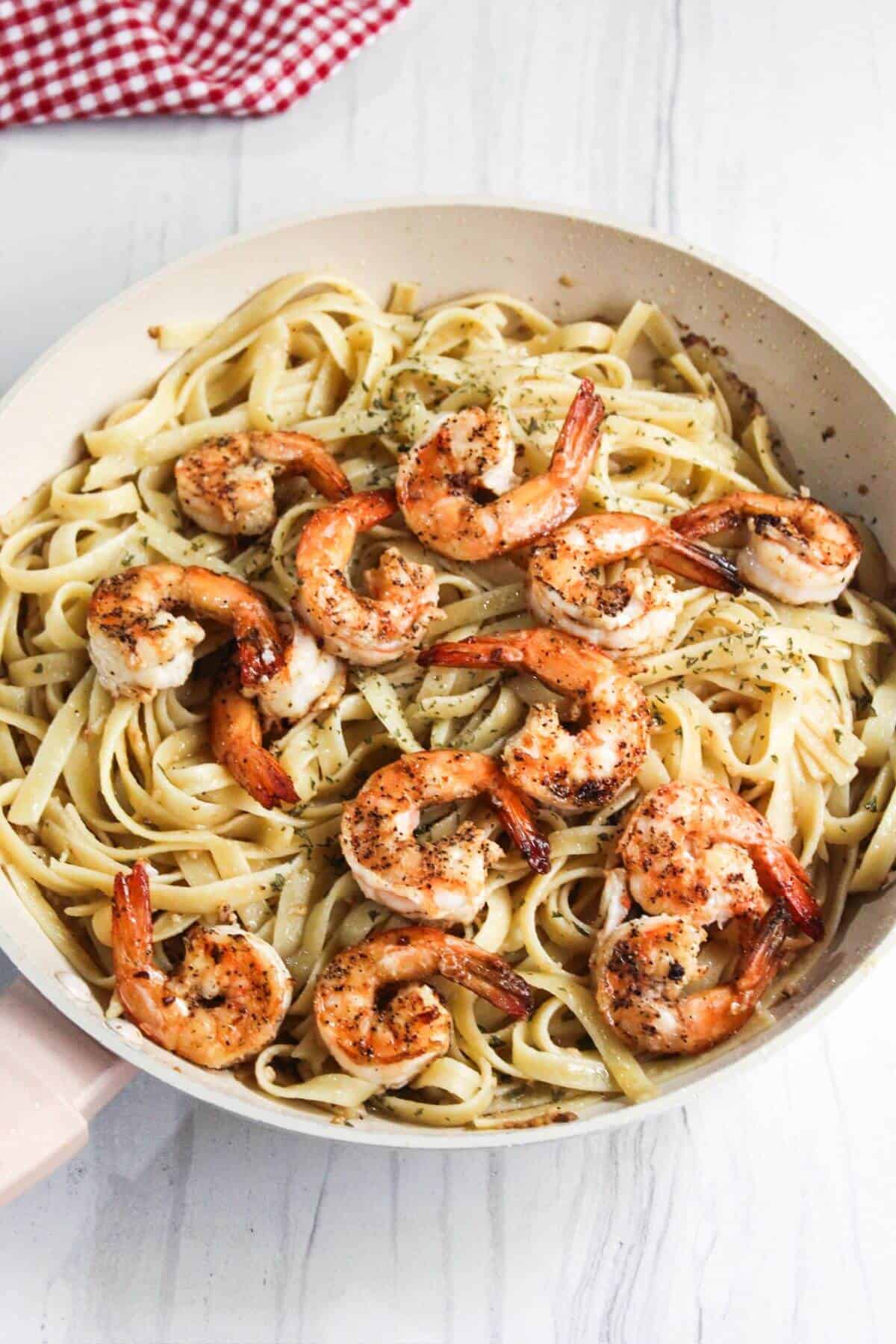 A pan with shrimp and pasta in it.