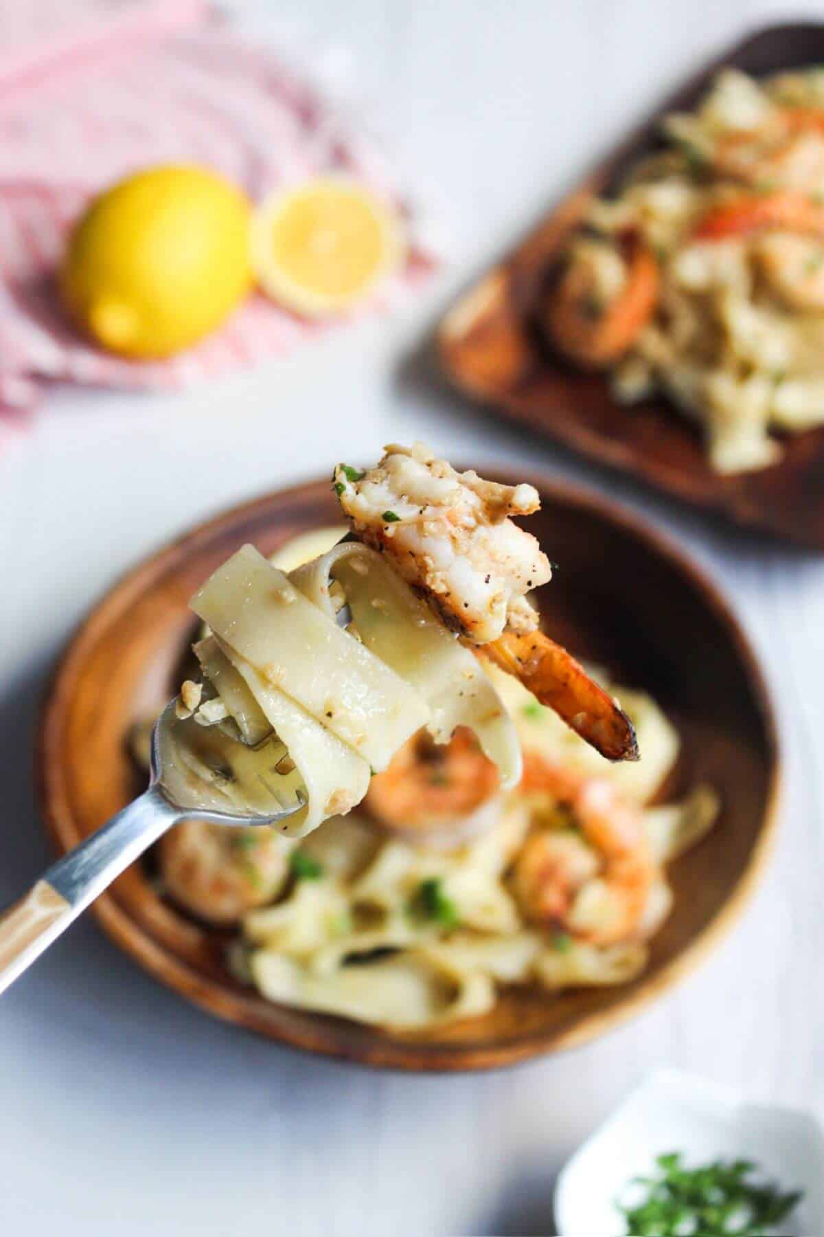 A spoon full of pasta with shrimp and lemon.