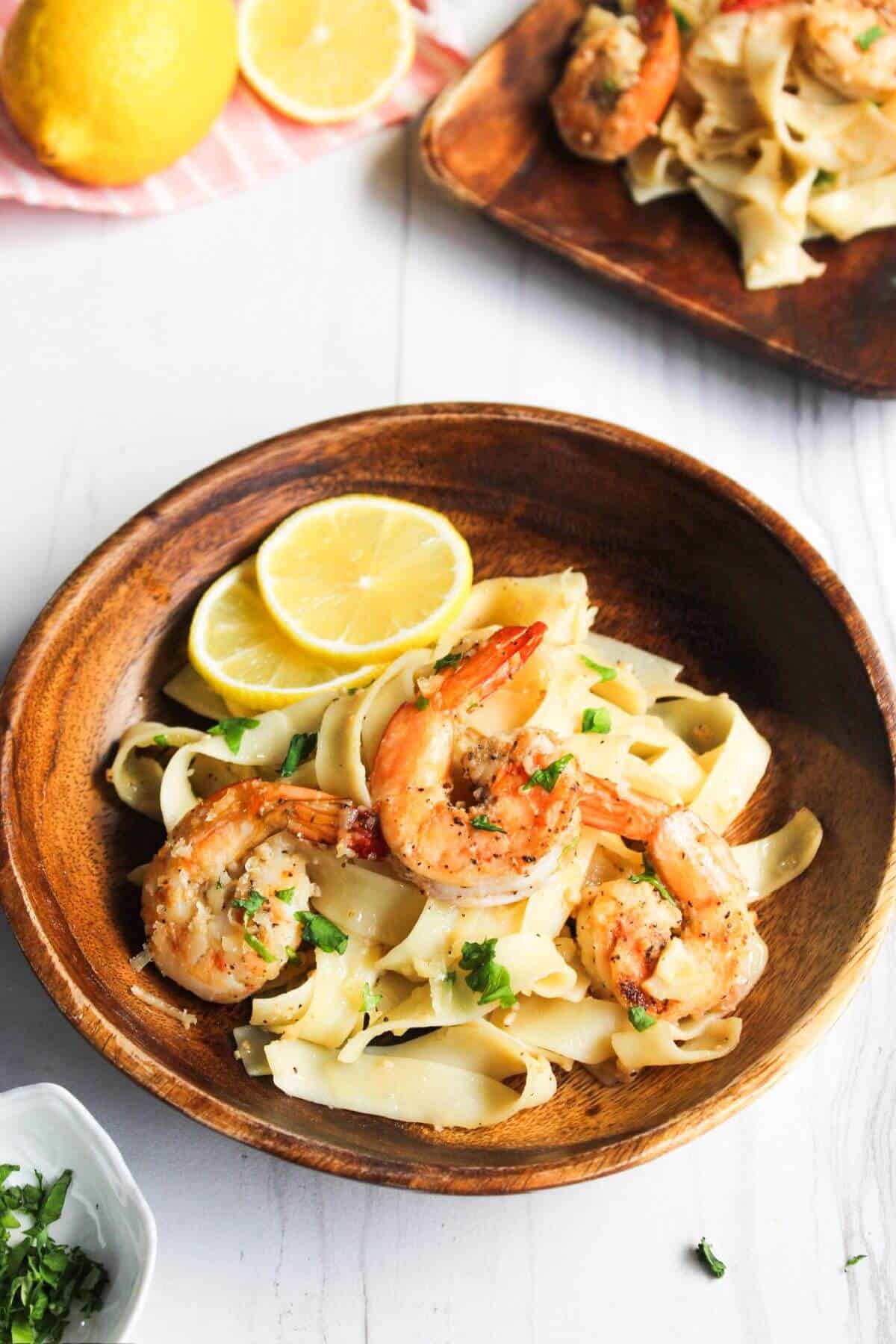 A bowl of pasta with shrimp and lemon slices.