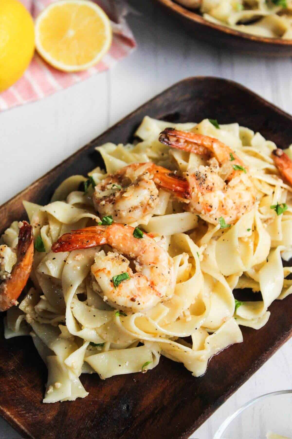 A plate of pasta with shrimp and lemon slices.