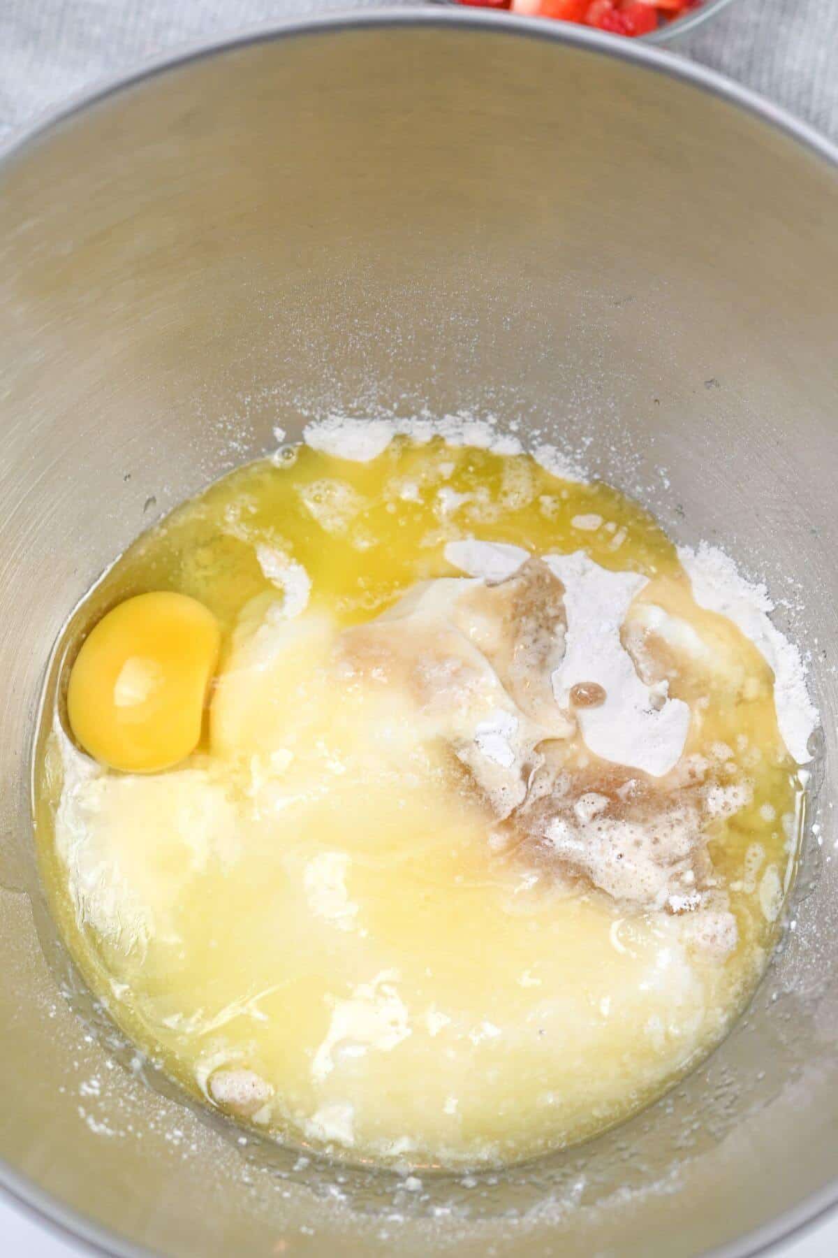 A mixing bowl with strawberry pound cake mixture, including eggs, flour, and sugar.